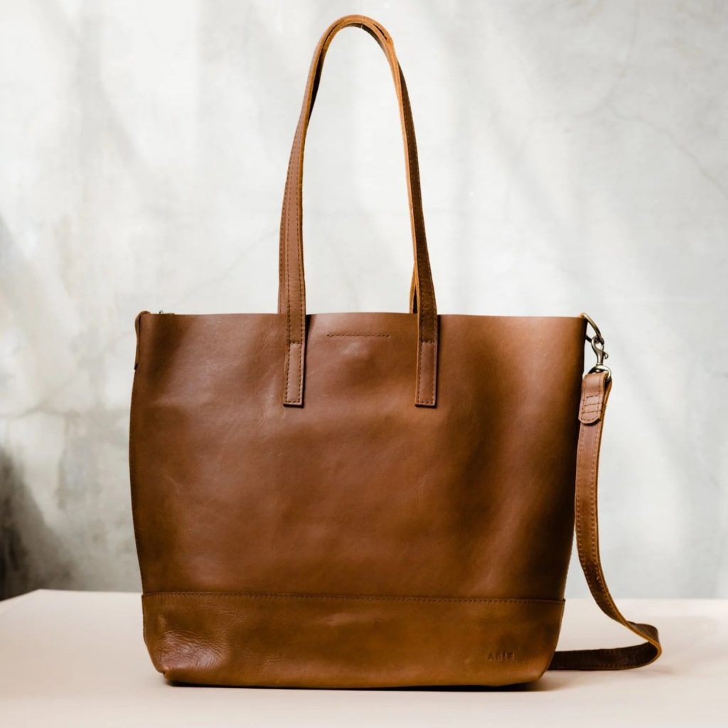A large brown leather tote bag from ethical brand ABLE for a sustainable capsule wardrobe handbag