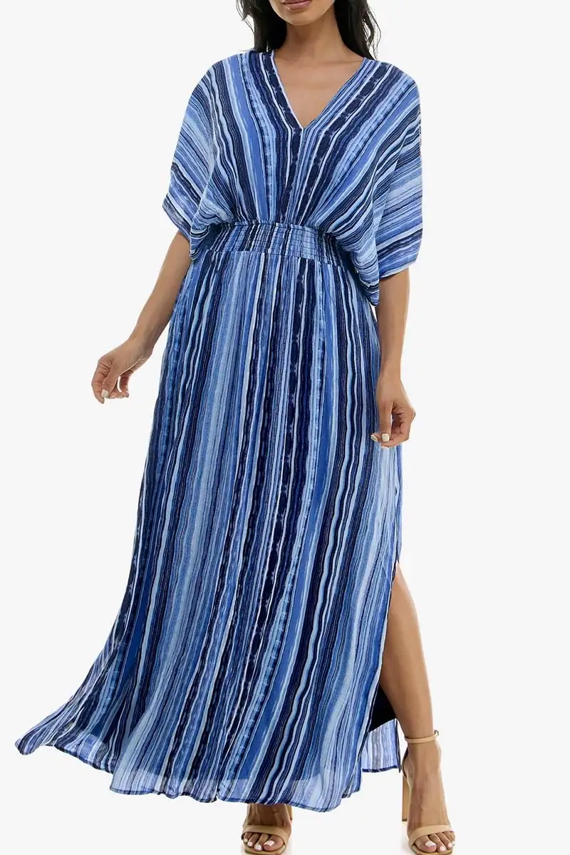 Model wears dolman sleeve dress with blue pattern against white background. 