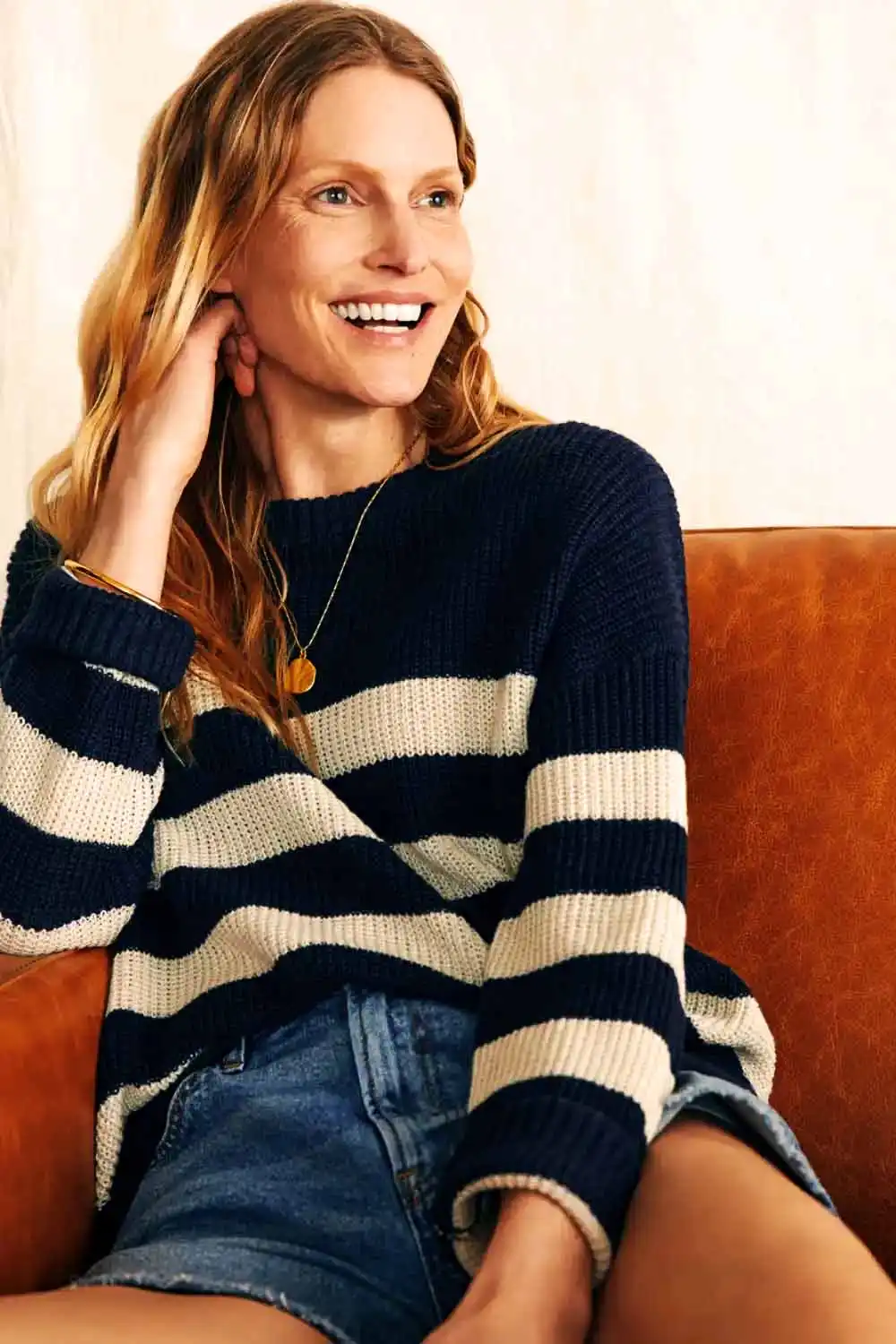 Smiling woman wearing striped crew neck sweater.