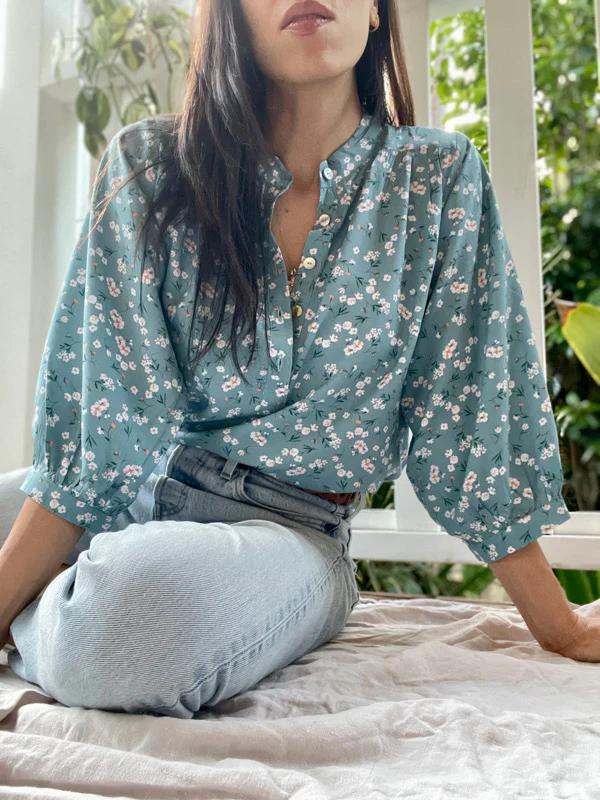woman wearing a sustainable blouse by a brand that empowers women called all the wild roses