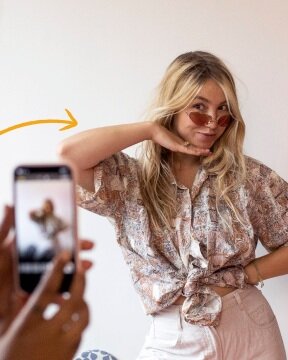 A young woman striking a pose in her secondhand clothing that she is uploading to the Vinted app to sell