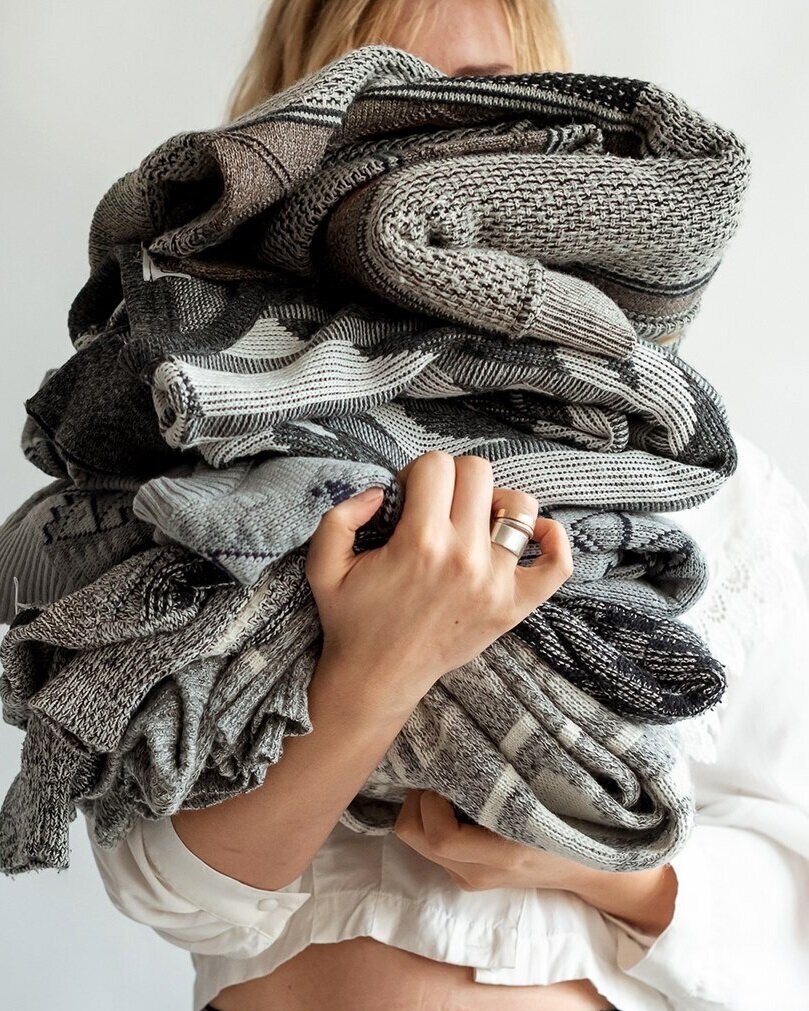 a woman holding a pile of secondhand sweaters from ASOS Marketplace