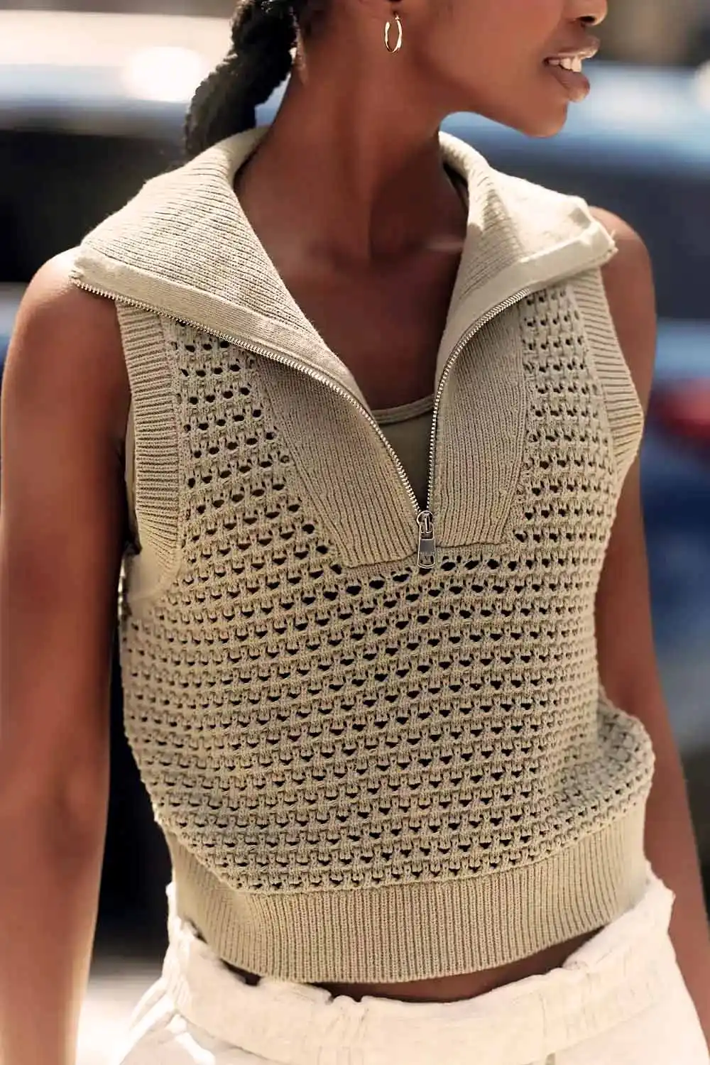 Close up of model wearing beige sleeveless sweater.
