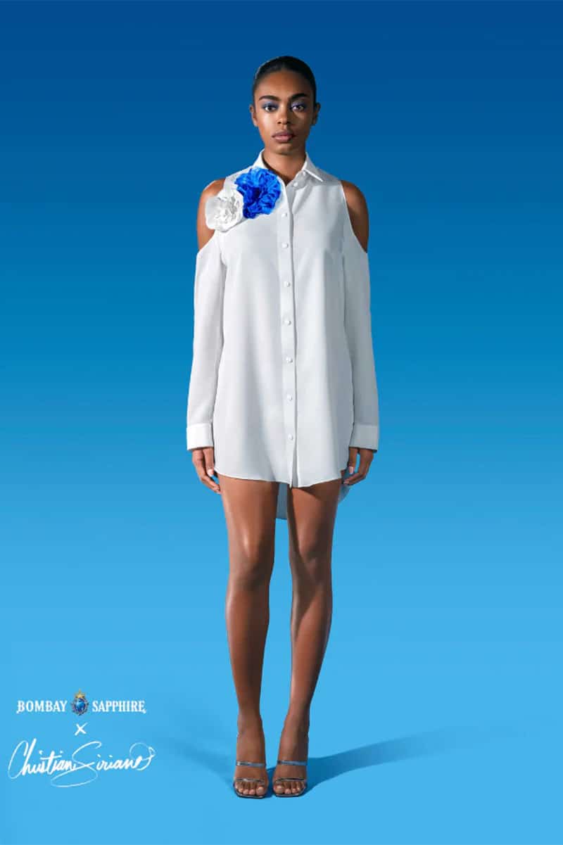 Model wears Christian Siriano and Bombay Sapphire dress against blue background. 