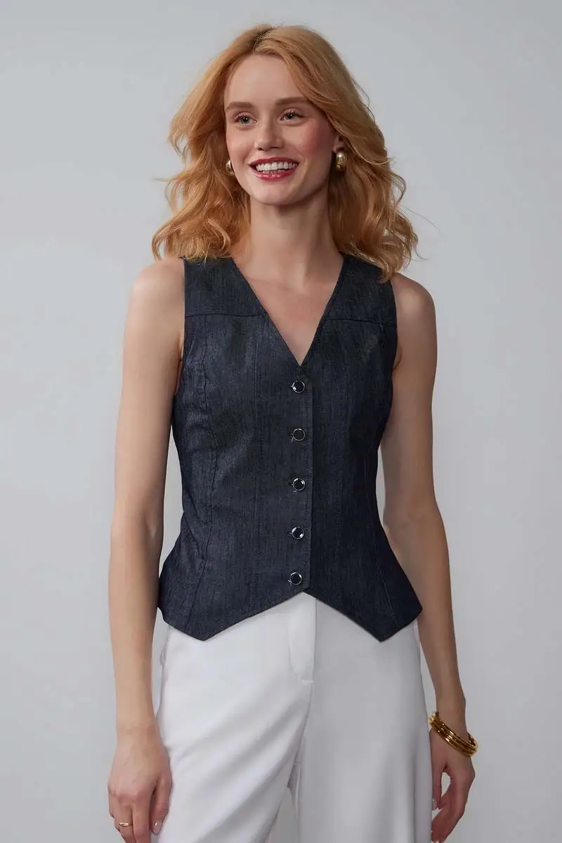 Model wears denim vest with white pants.
