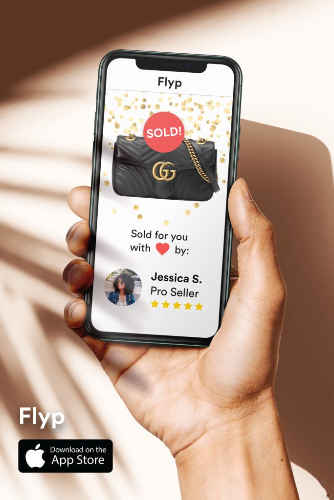 A hand holding an iPhone with a secondhand clothing app call Flyp