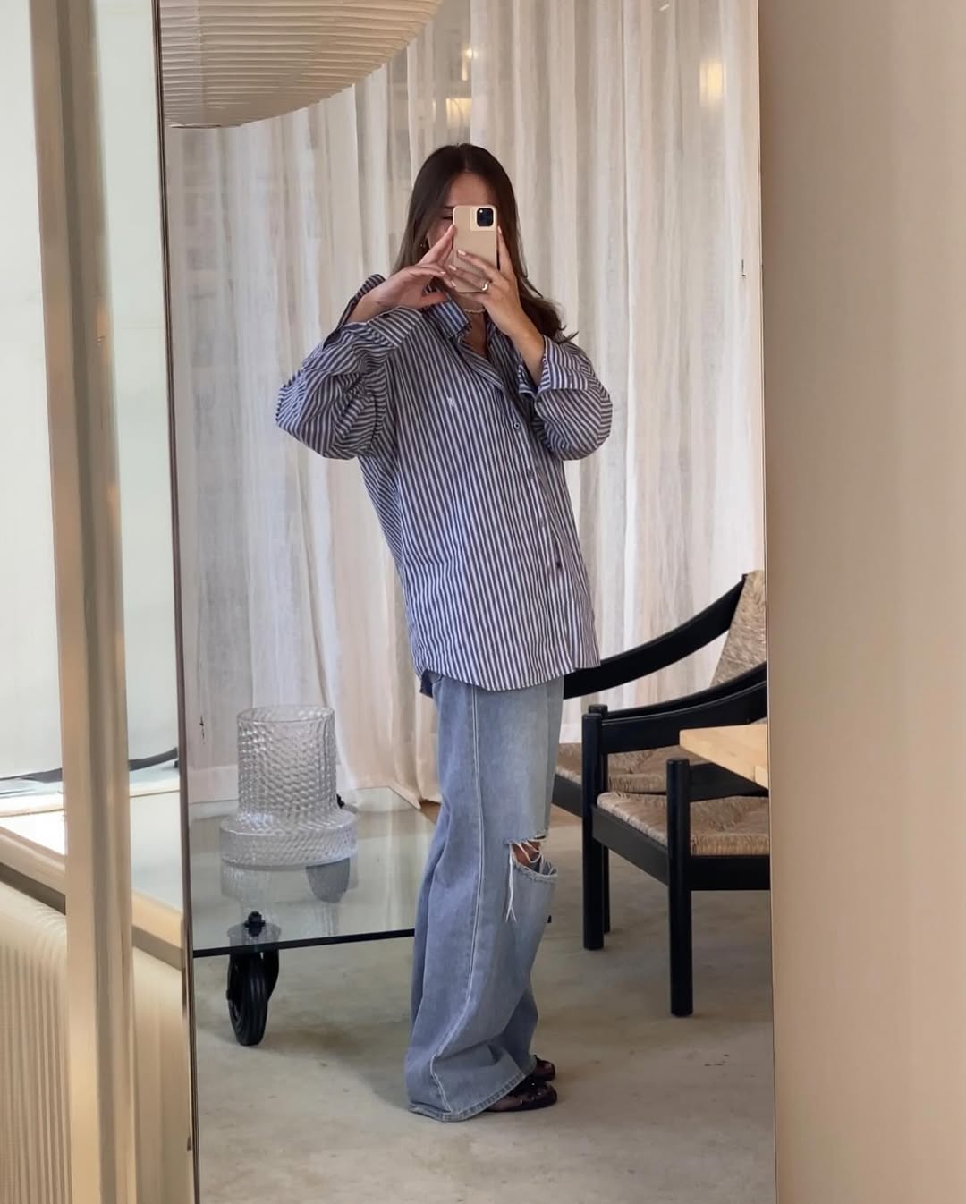 Woman wearing baggy jeans and oversize striped button-down shirt in a summer 2025 outfit.