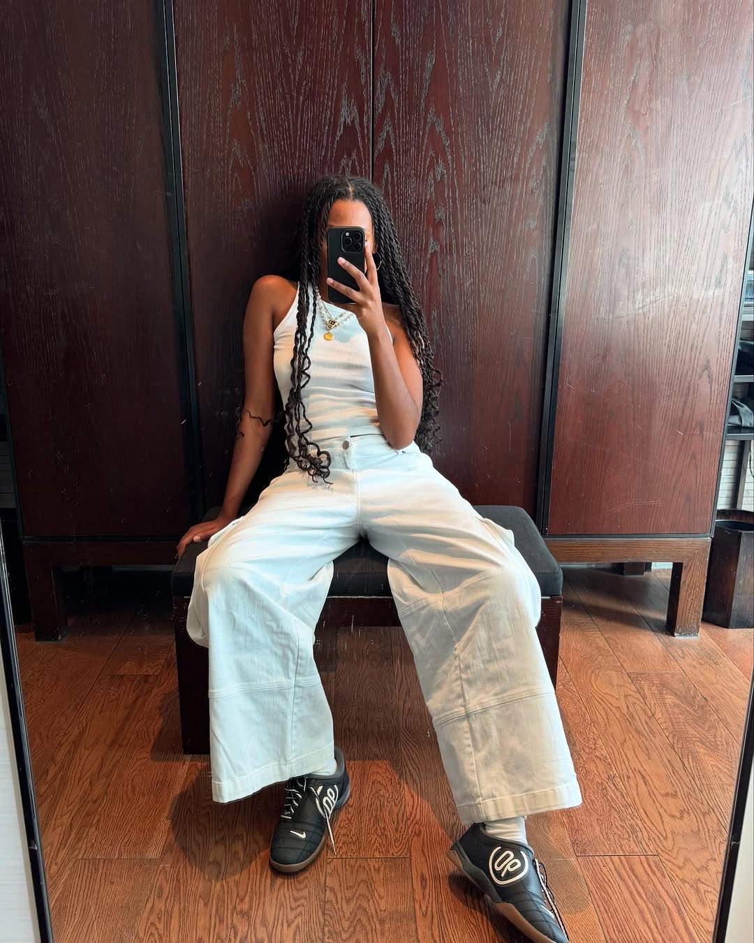 Woman wearing white tank and white wide jeans with sneakers in a summer 2025 outfit.