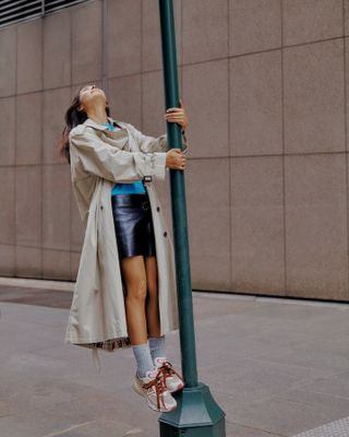 New York-based fashion influencer @himichelleli wearing a stylish spring outfit with a trench coat and sneakers.