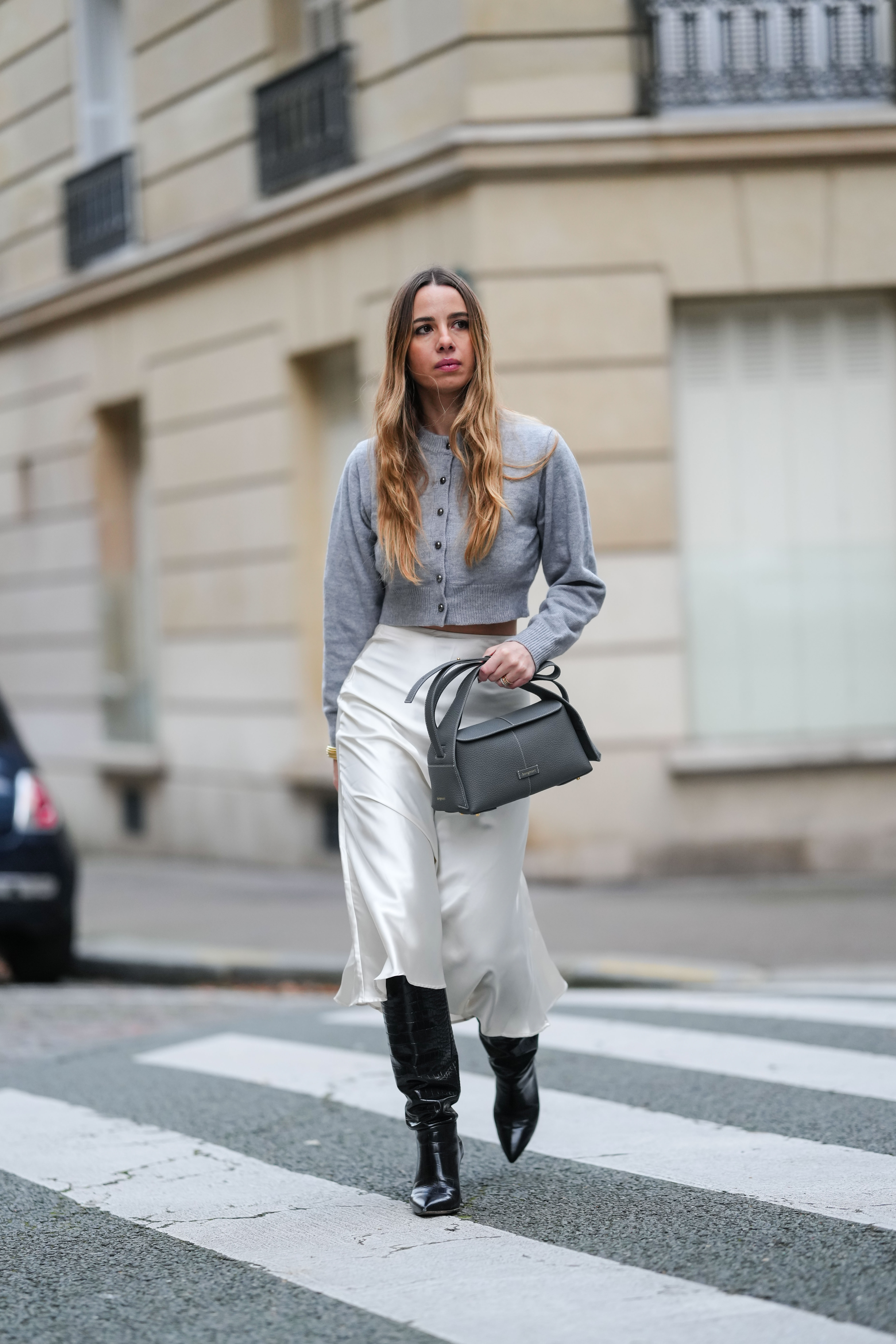 Street style photo of woman wearing slip skirt and boots.