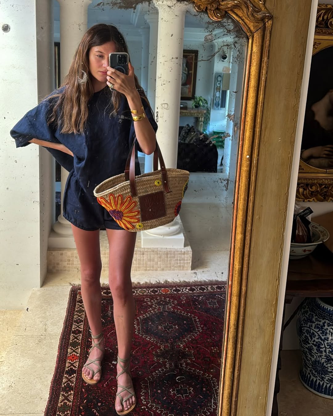 Woman wearing blue matching short set with raffia bag in a summer 2025 outfit.