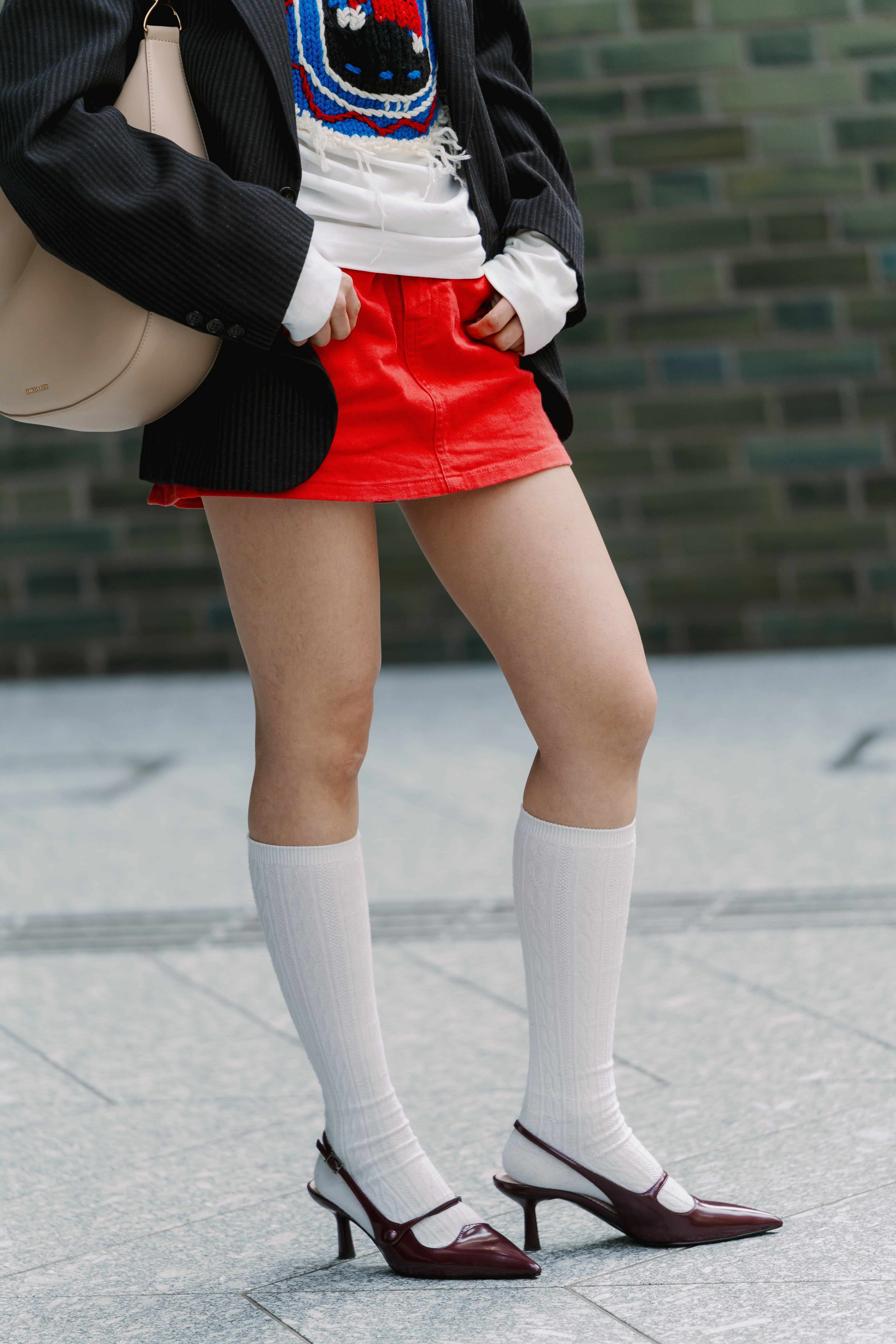 Photo of woman wearing red skirt, slingback heels, and white knee-high socks in Tokyo.