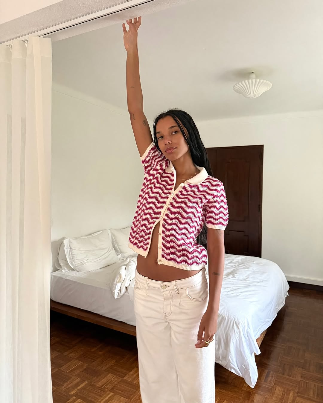 Woman wearing white jeans and short-sleeve striped sweater in a summer 2025 outfit.