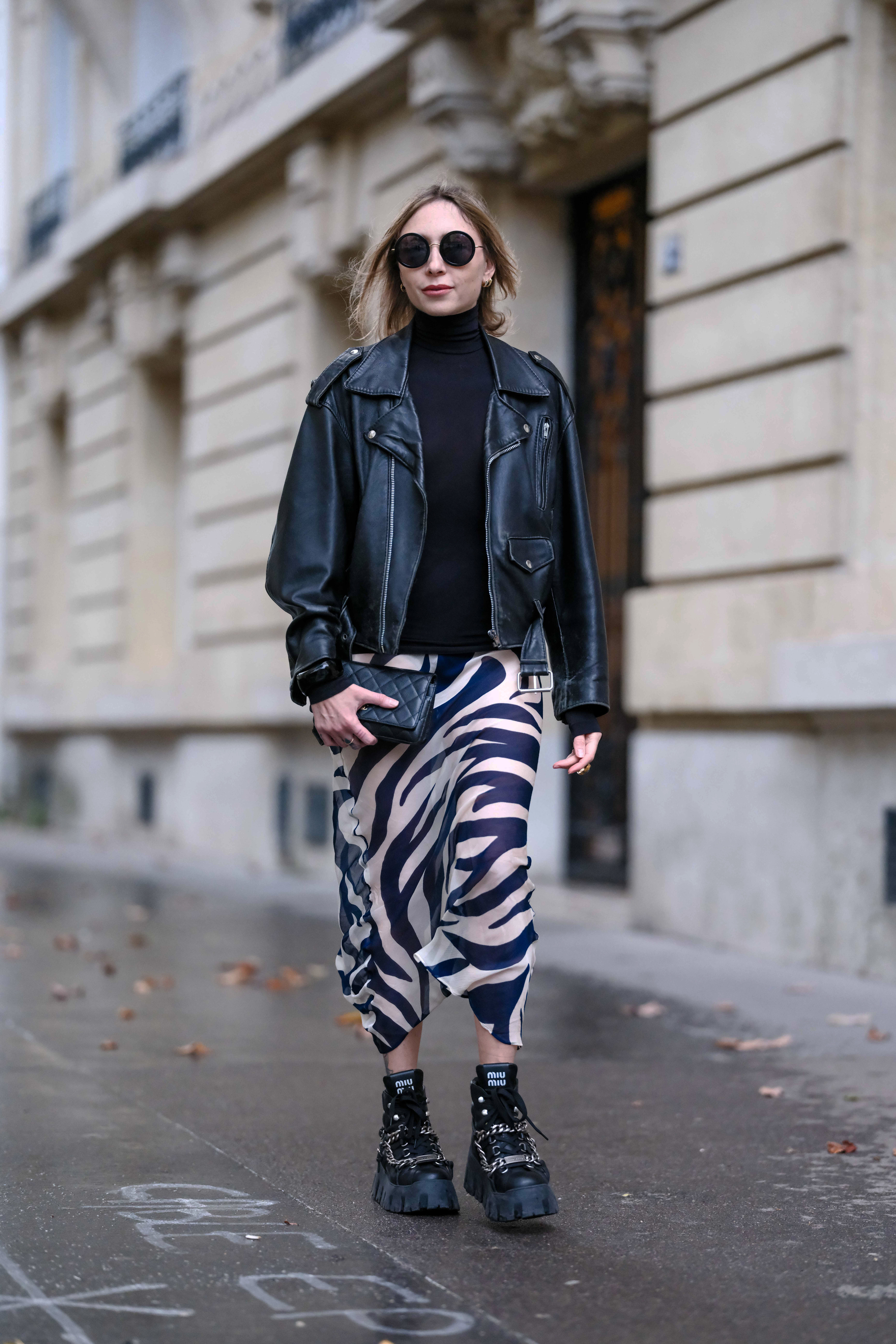 Street style photo of woman wearing slip skirt and boots.