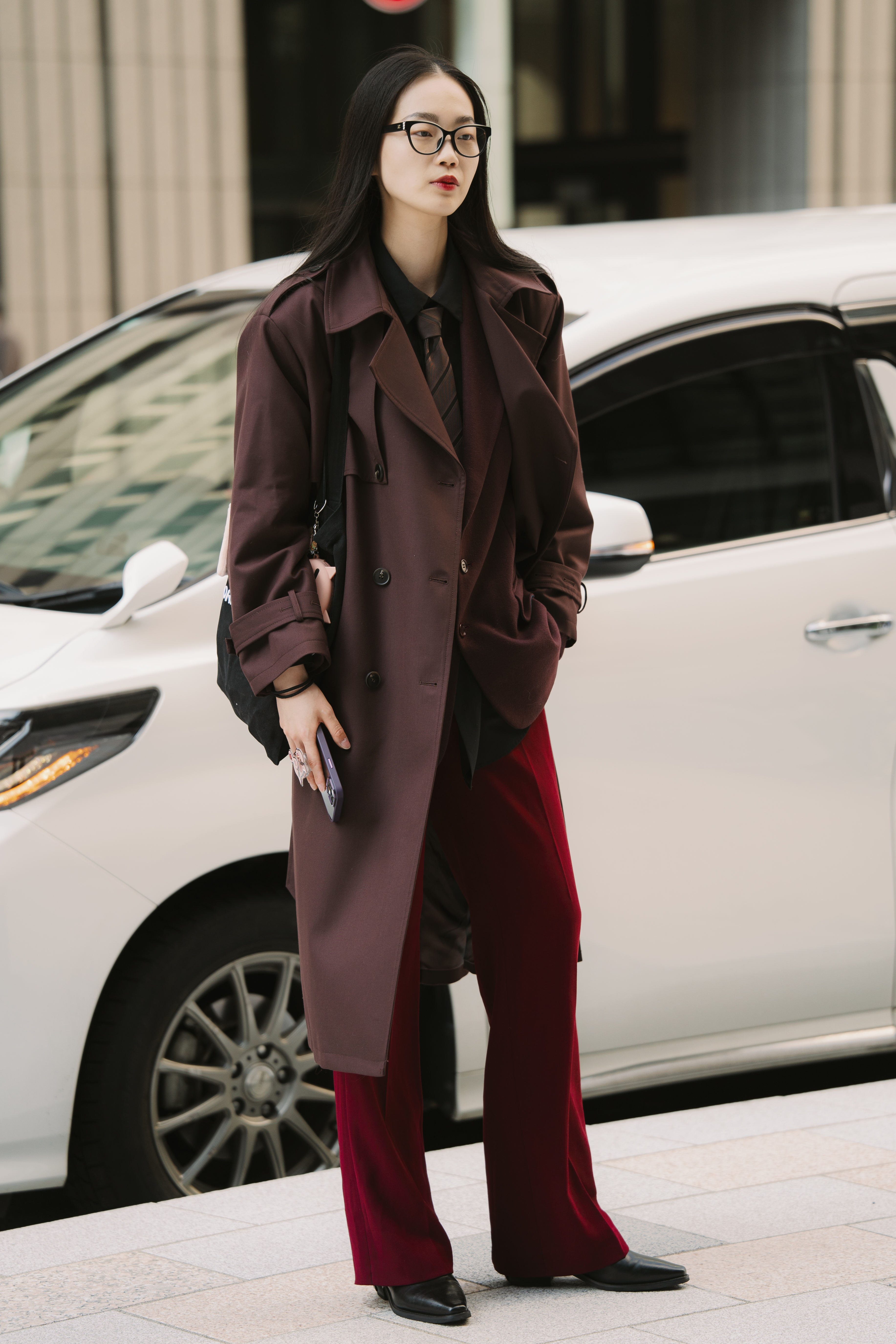 Photo of woman wearing brown coat, red pants, and men's dress tie in Tokyo.