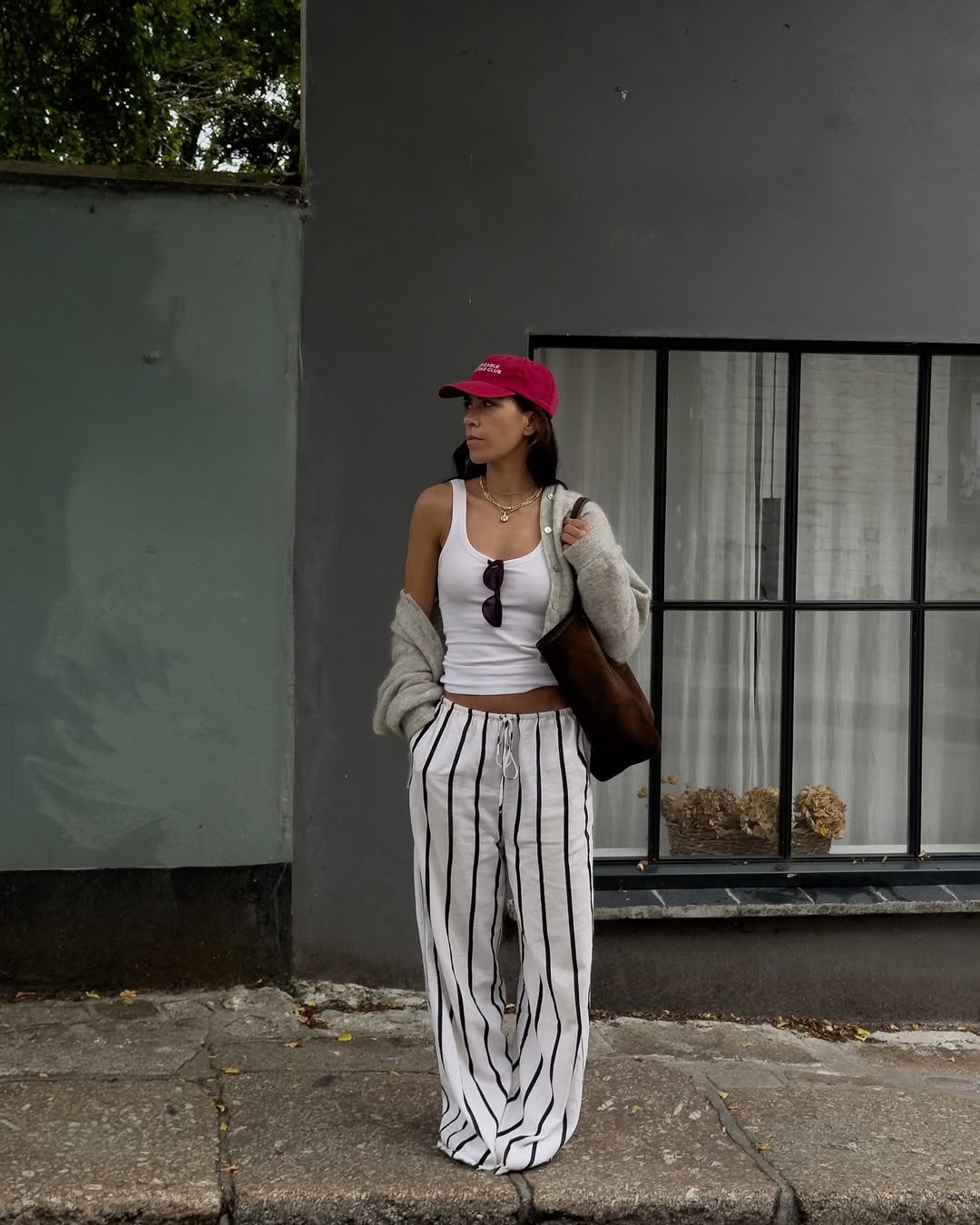 woman wearing loose pants and fitted tank with red baseball cap