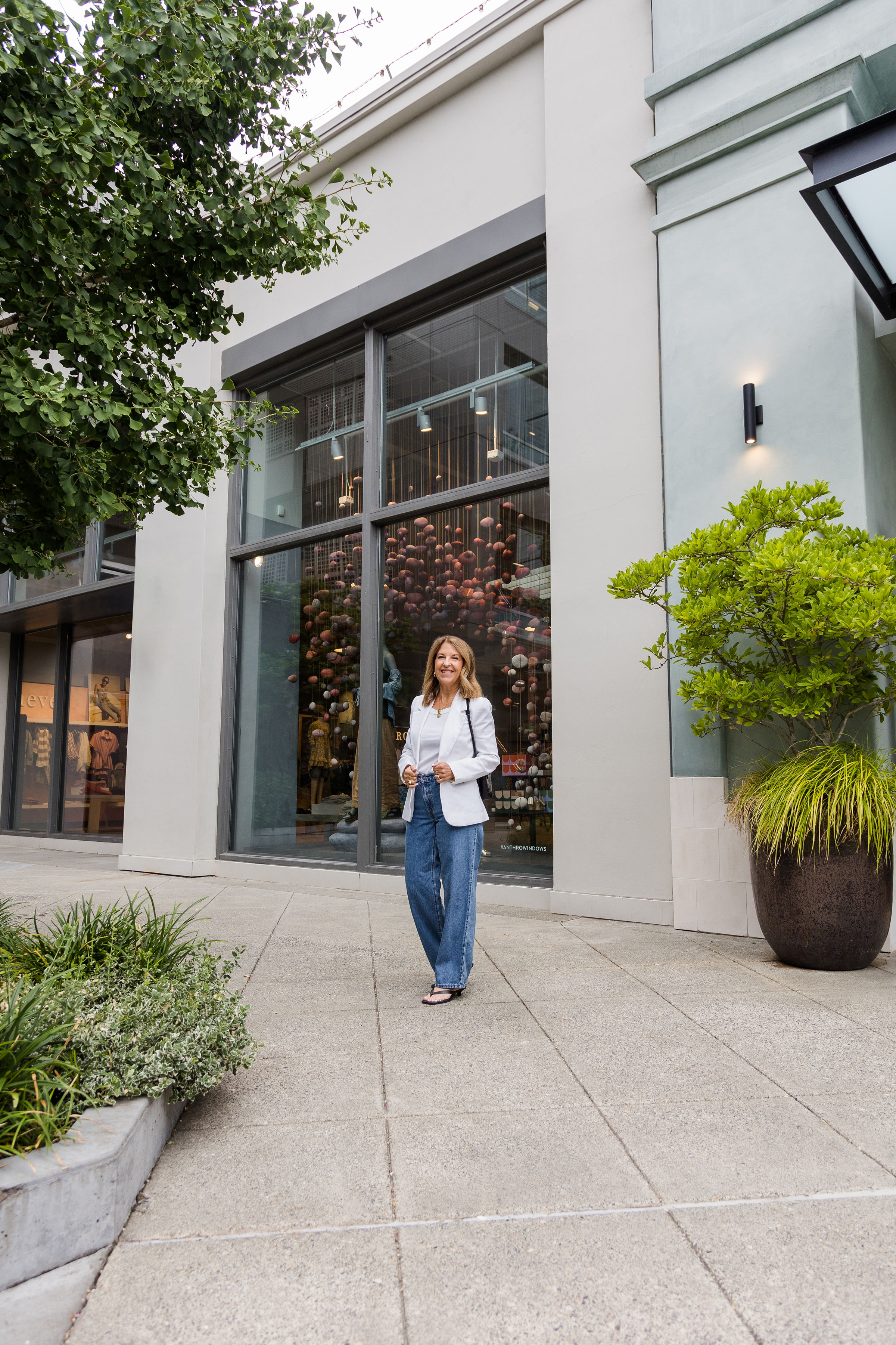 A Nordstrom stylist wearing baggy jeans, a white top, and a white blazer.