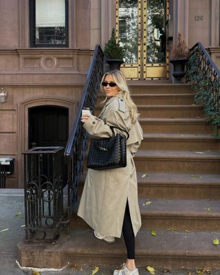 New York-based fashion influencer @fredrika_ekerot wearing a stylish spring outfit with a trench coat and sneakers.