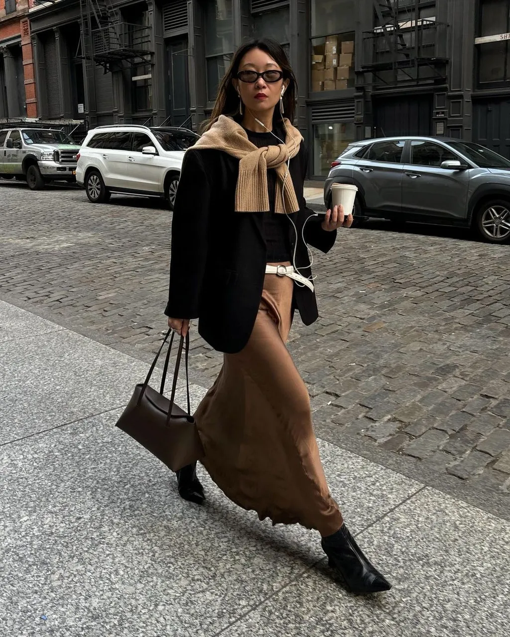 Street style photo of woman wearing slip skirt and boots.