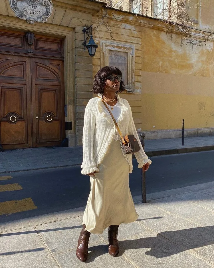 Street style photo of woman wearing slip skirt and boots.