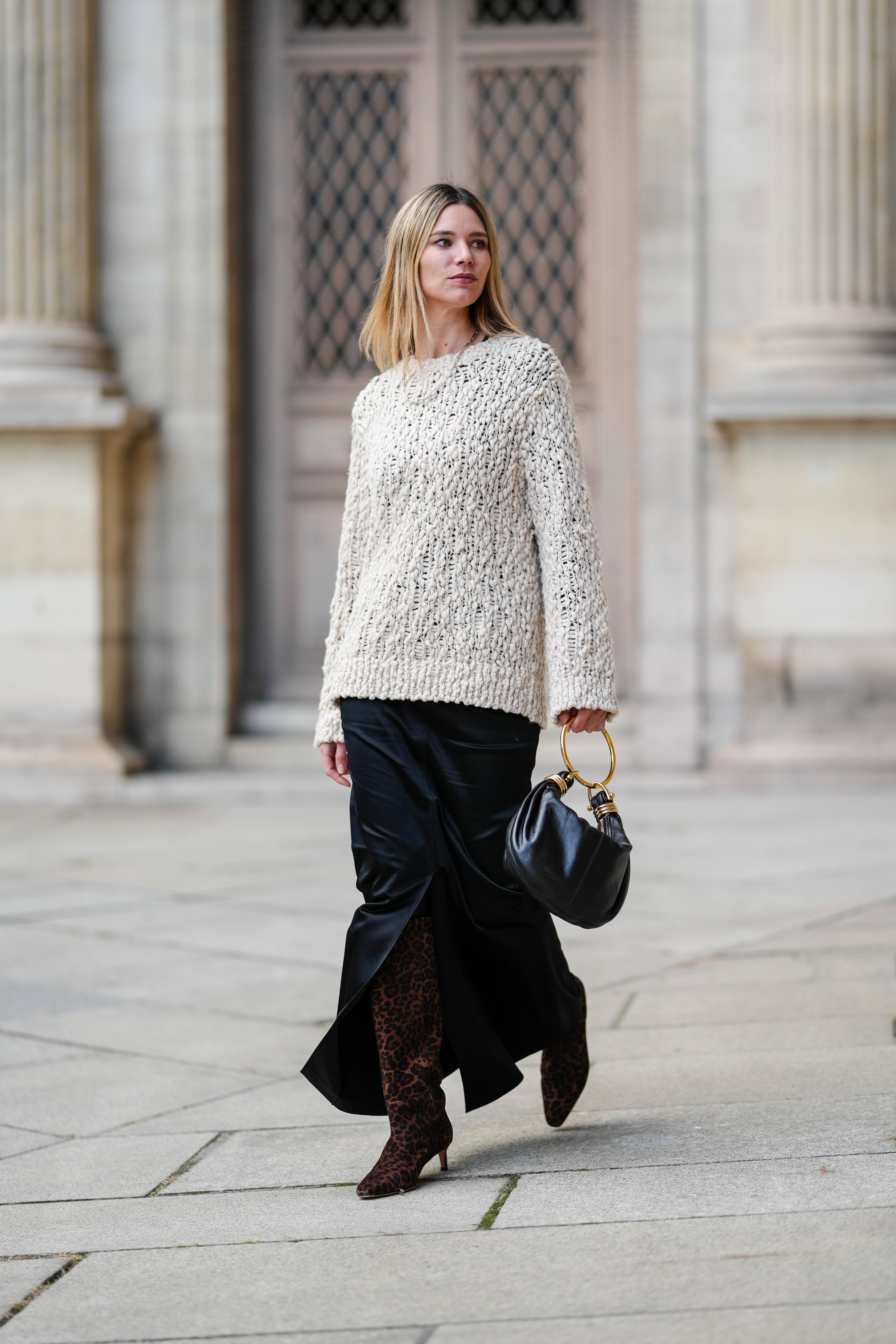 Street style photo of woman wearing slip skirt and boots.