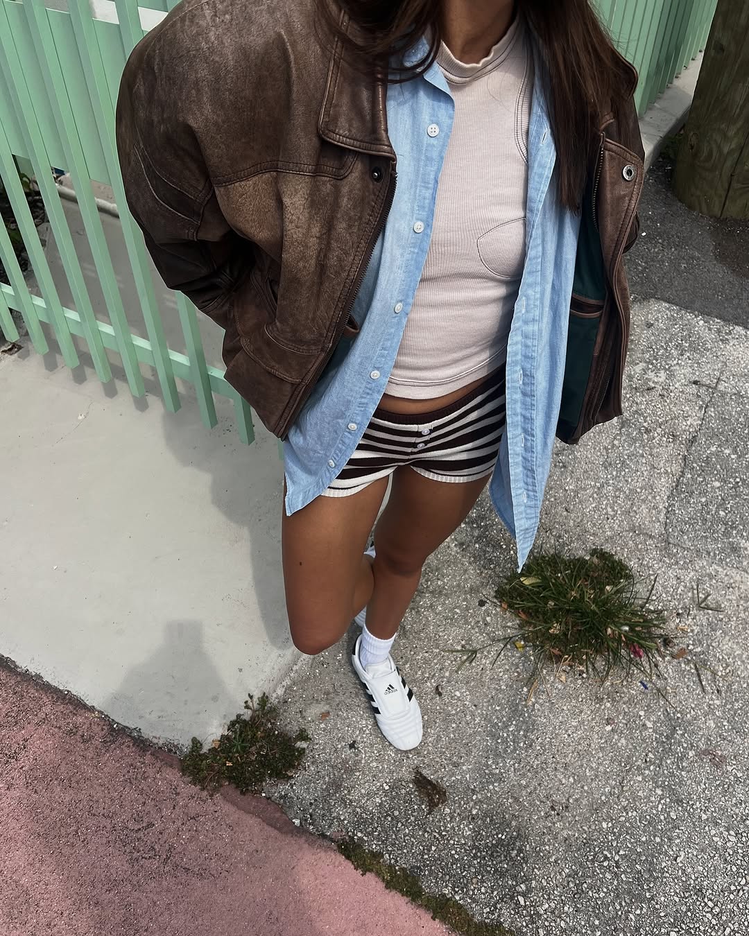 woman wearing micro shorts with white tank and leather bomber jacket