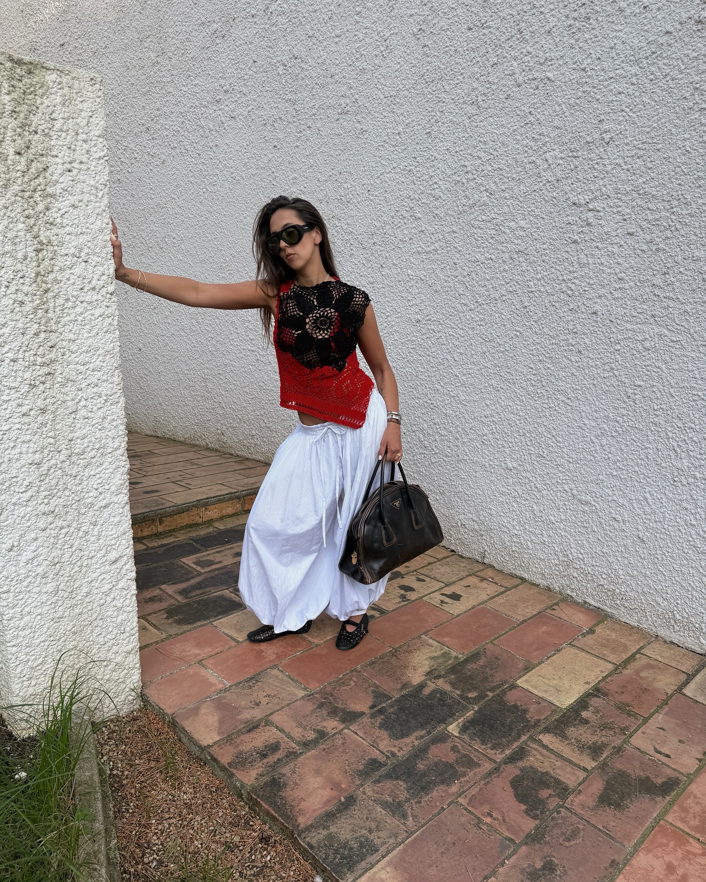 Hanna MW wearing a black-and-red crochet top and white genie pants.
