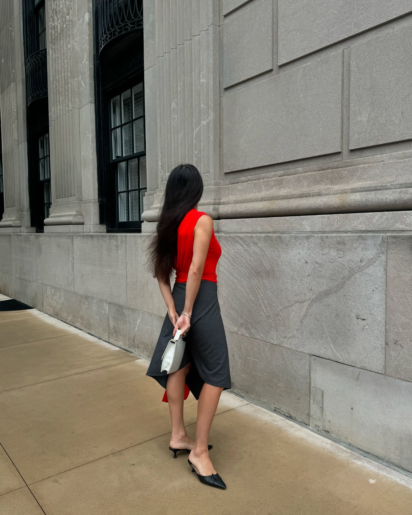 Alexis Badiyi wearing a red vest, gray skirt, and cream bag.