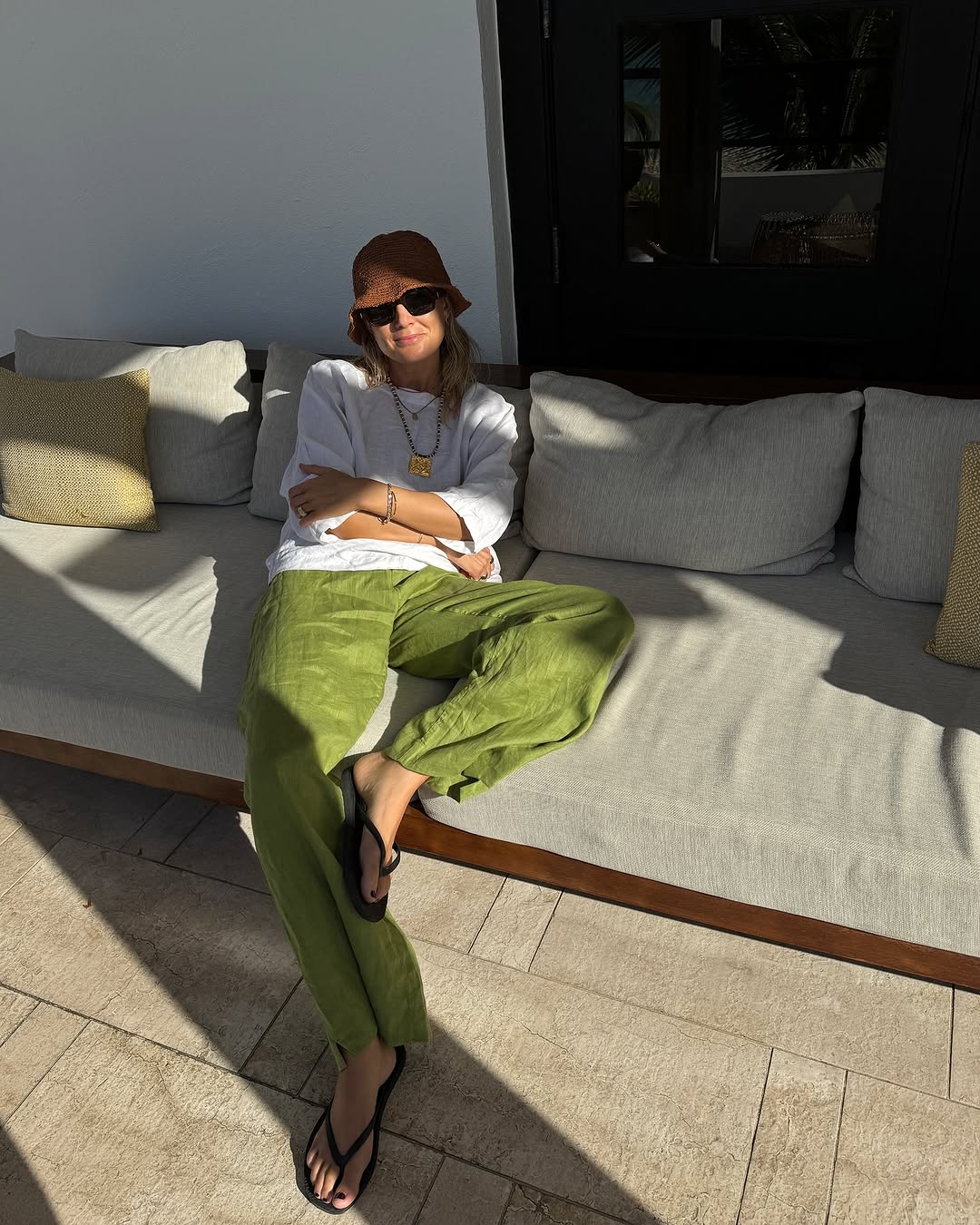 woman wearing green pants and t-shirt with brown bucket hat on vacation
