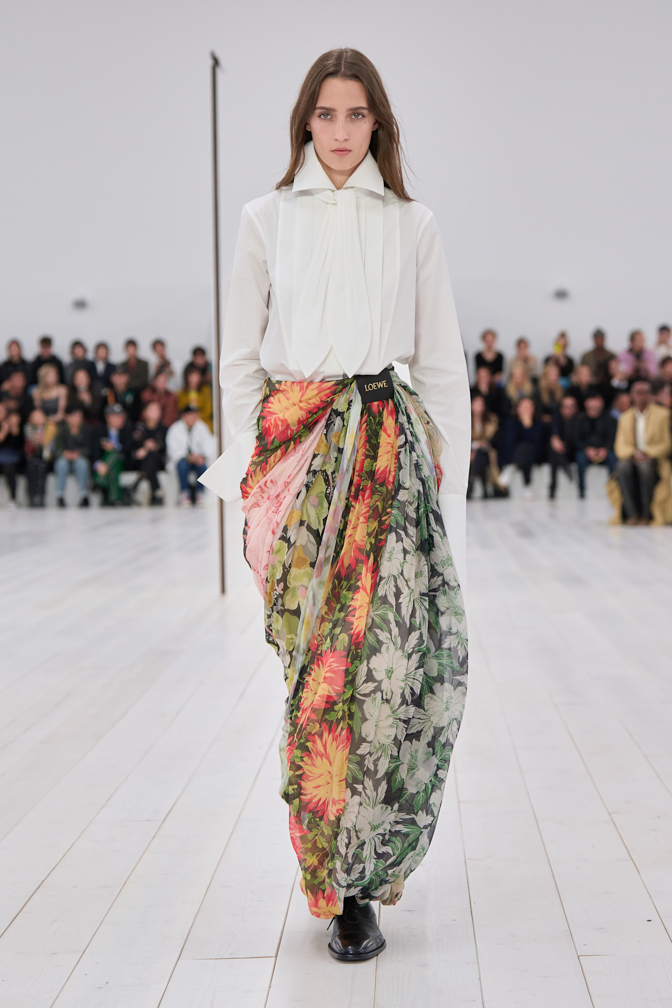 A model wearing a white shirt and floral genie pants on the runway at Loewe's spring/summer 2025 show.