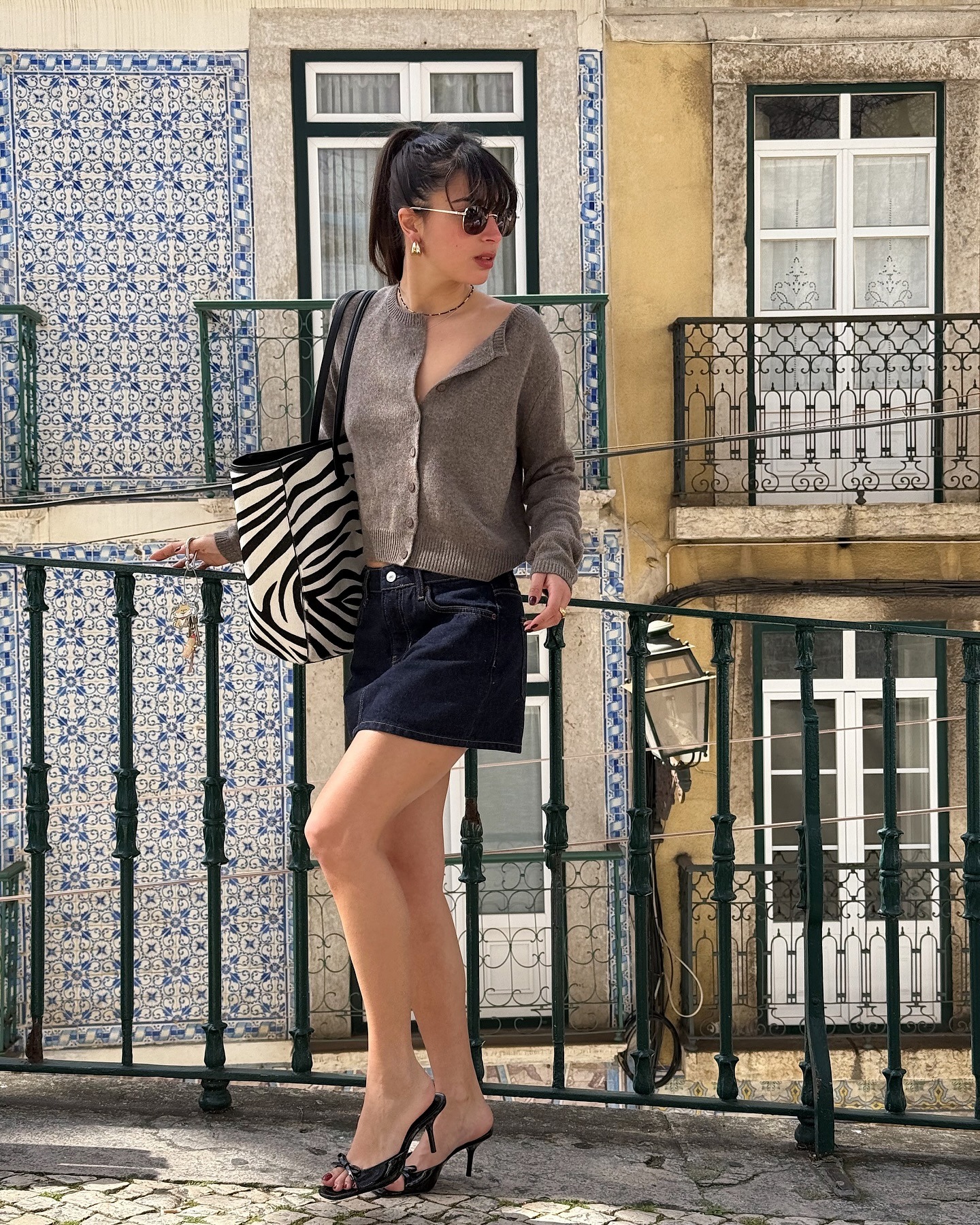 '90s-inspired outfit including a cardigan, denim miniskirt, and heels