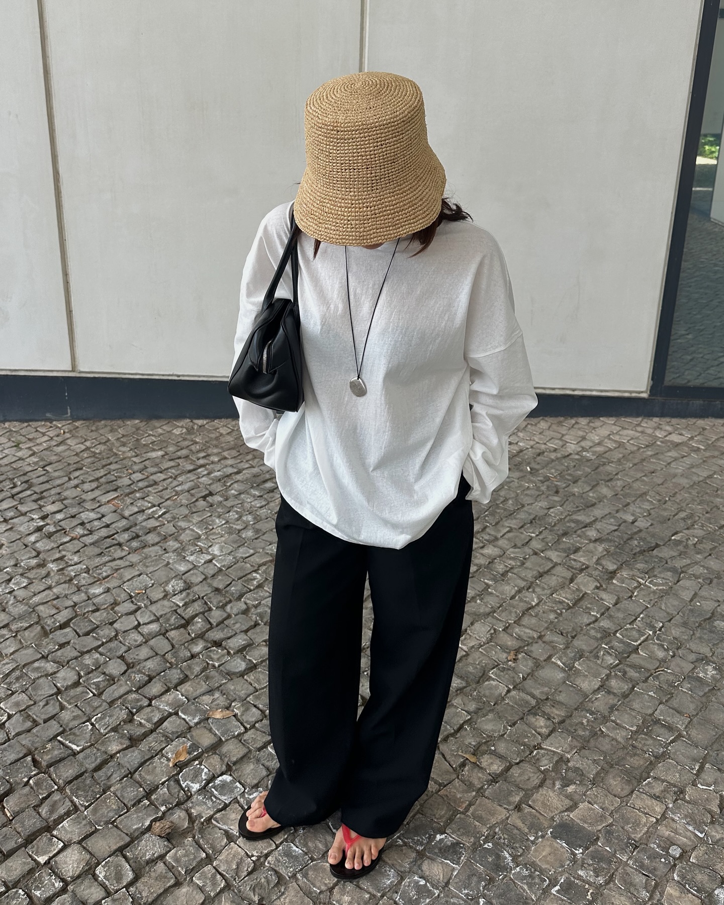 Debora Rosa wearing a straw hat, white T-shirt, and black drawstring pants with red flip flops.