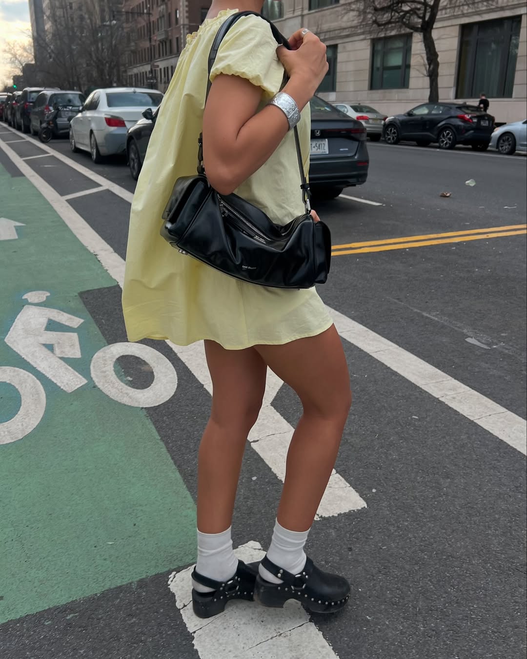 woman wearing yellow minidress with black clogs and socks in nyc summer outfit