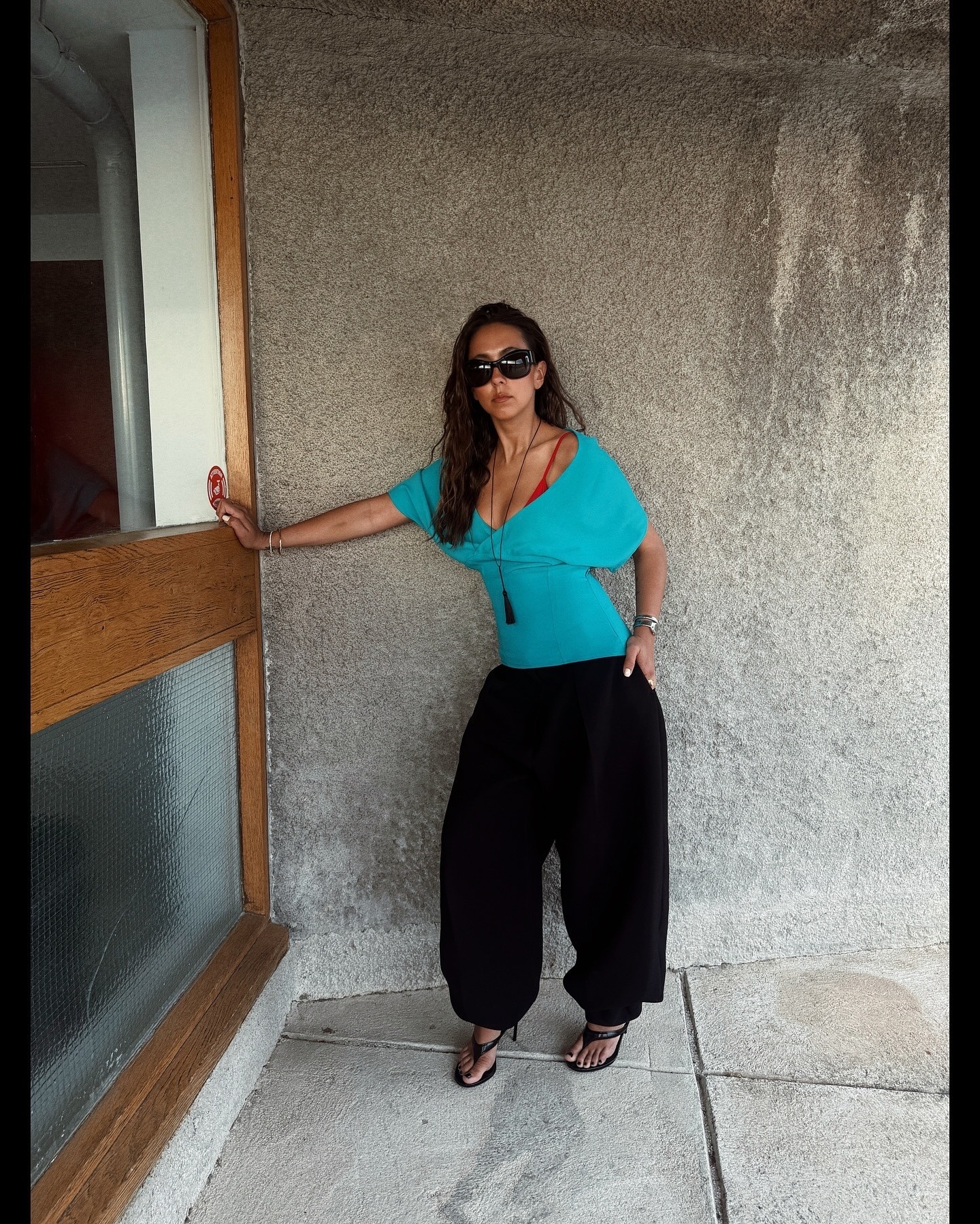 Hanna MW wearing a turquoise off-the-shoulder top with black genie pants and sandals.
