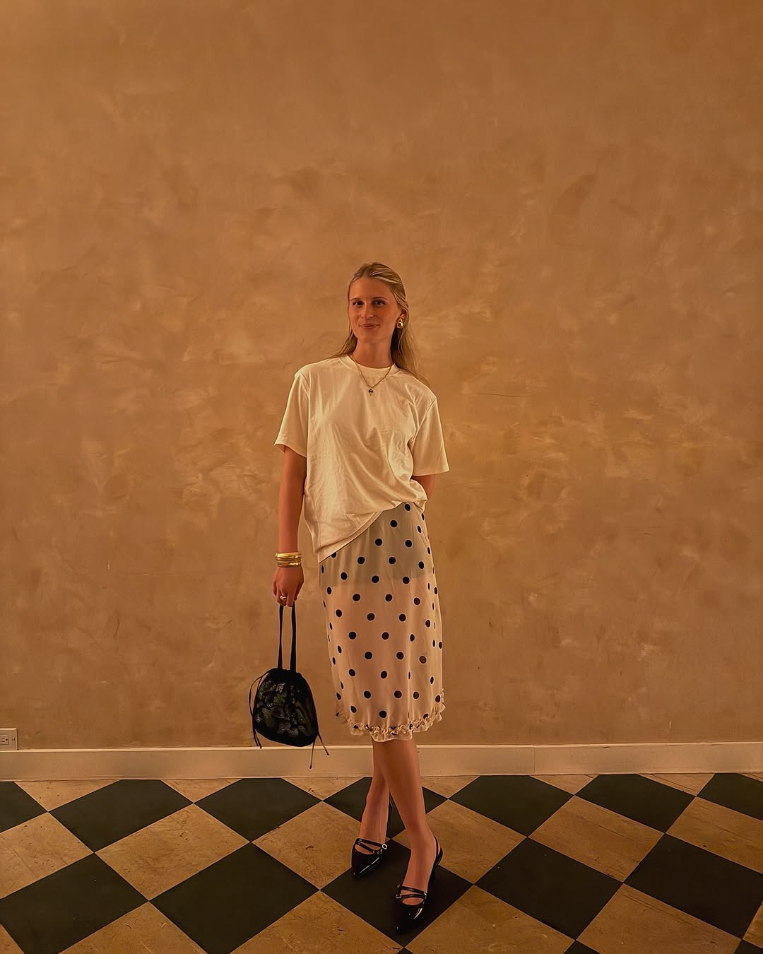 A woman wearing white t-shirt and knee-length skirt summer 2025.