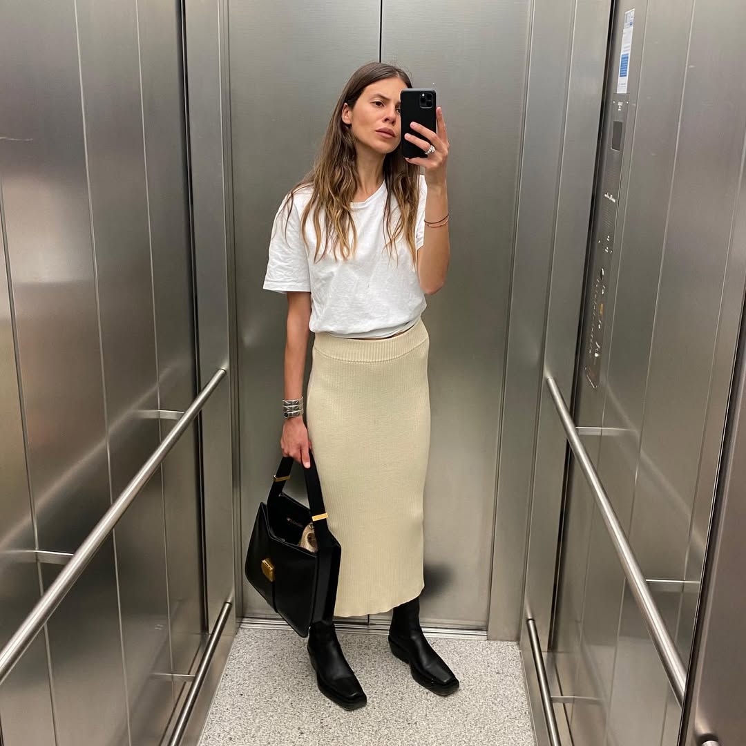 A woman wearing white t-shirt and long skirt summer 2025.