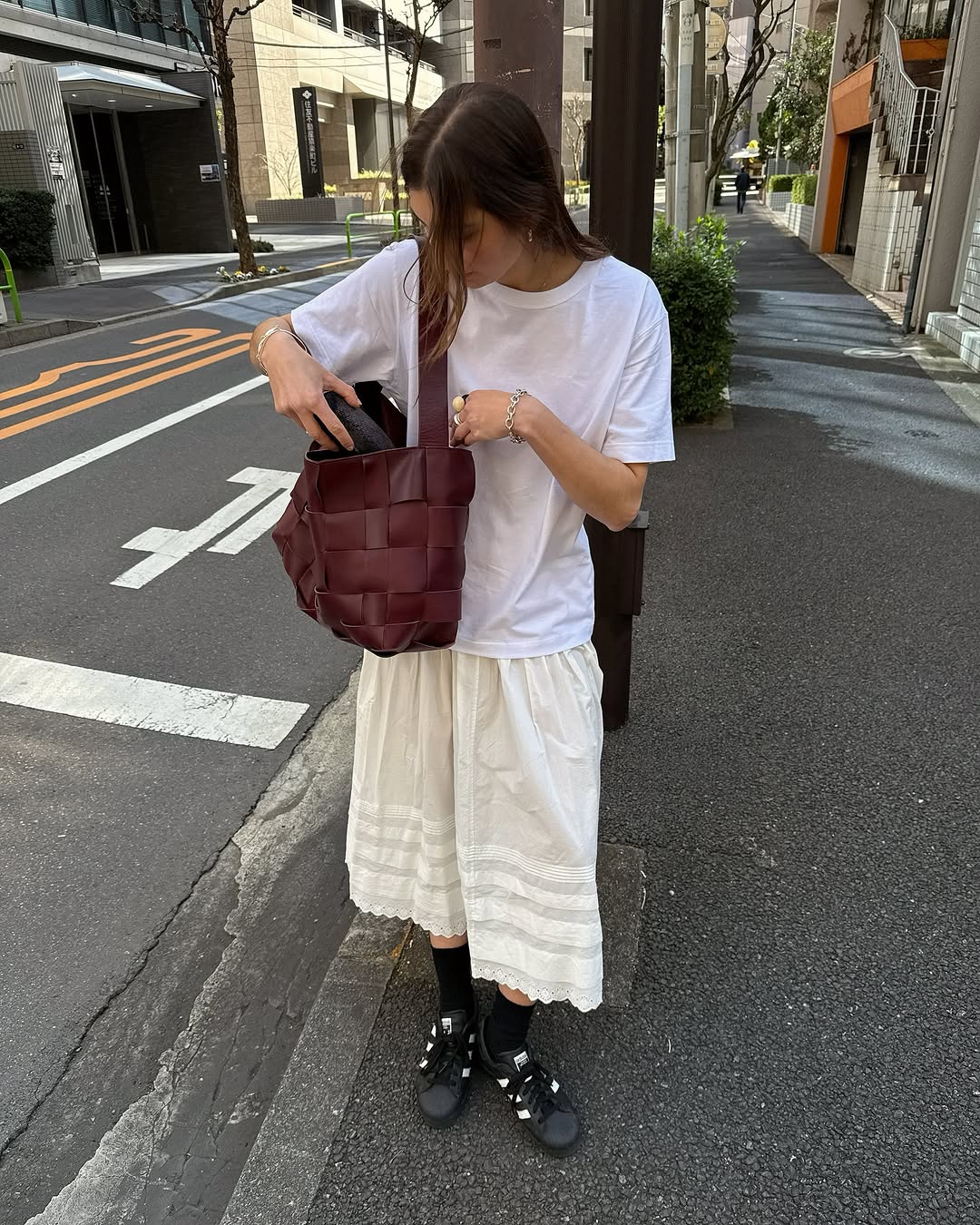 A woman wearing white t-shirt and knee-length skirt summer 2025.