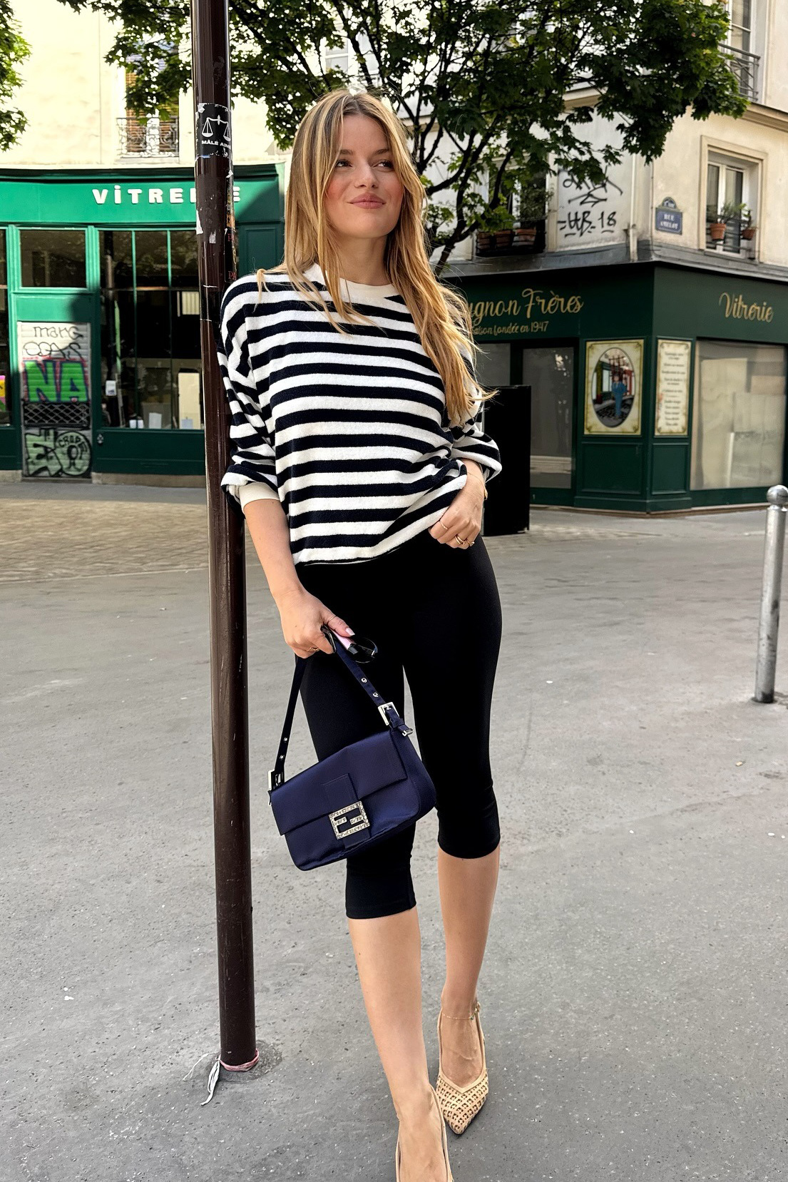 French influencer wearing a striped shirt and capri pants