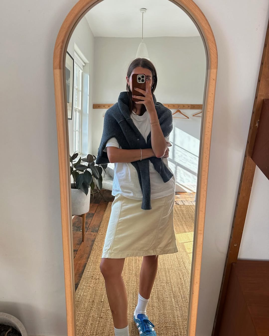 A woman wearing white t-shirt and knee-length skirt summer 2025.