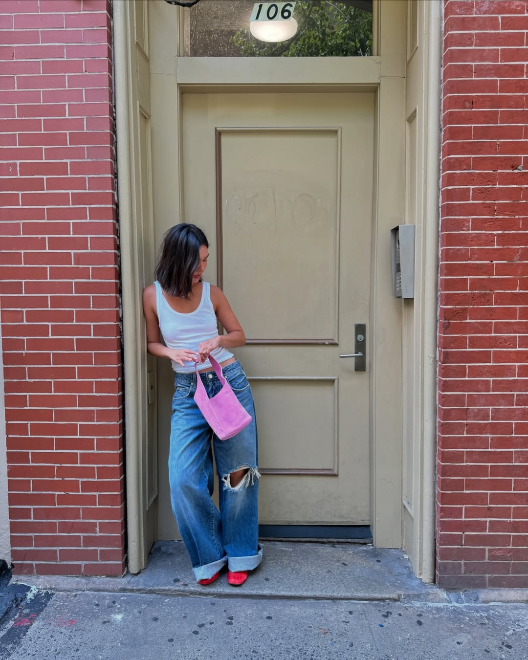 Woman wearing vintage jeans with white tank and cool bag.