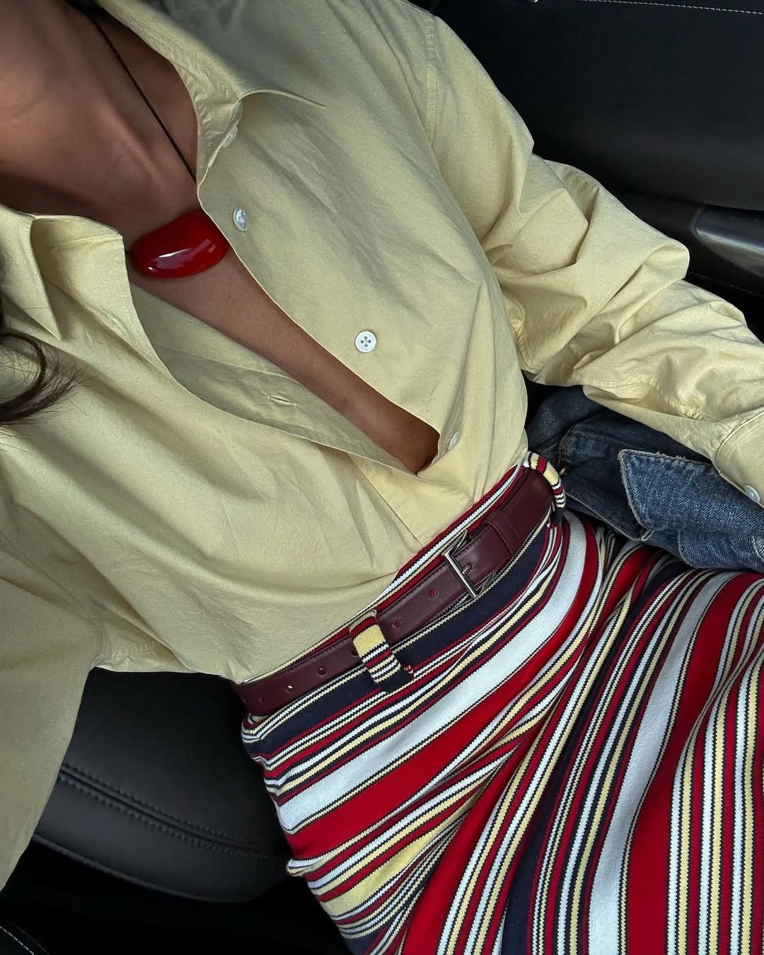 Woman wearing a striped skirt and a pale yellow button-down.