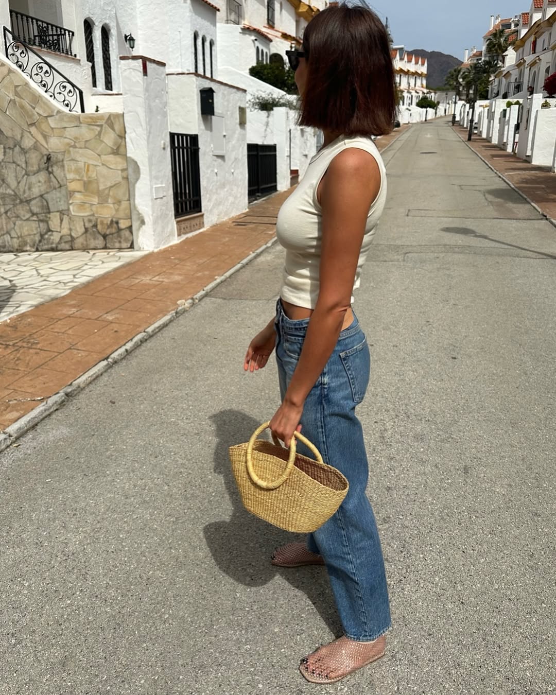 Woman wearing vintage jeans with white tank and cool bag.