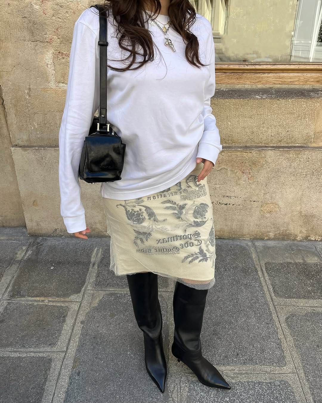 Woman wearing white t-shirt and midi skirt summer 2025.