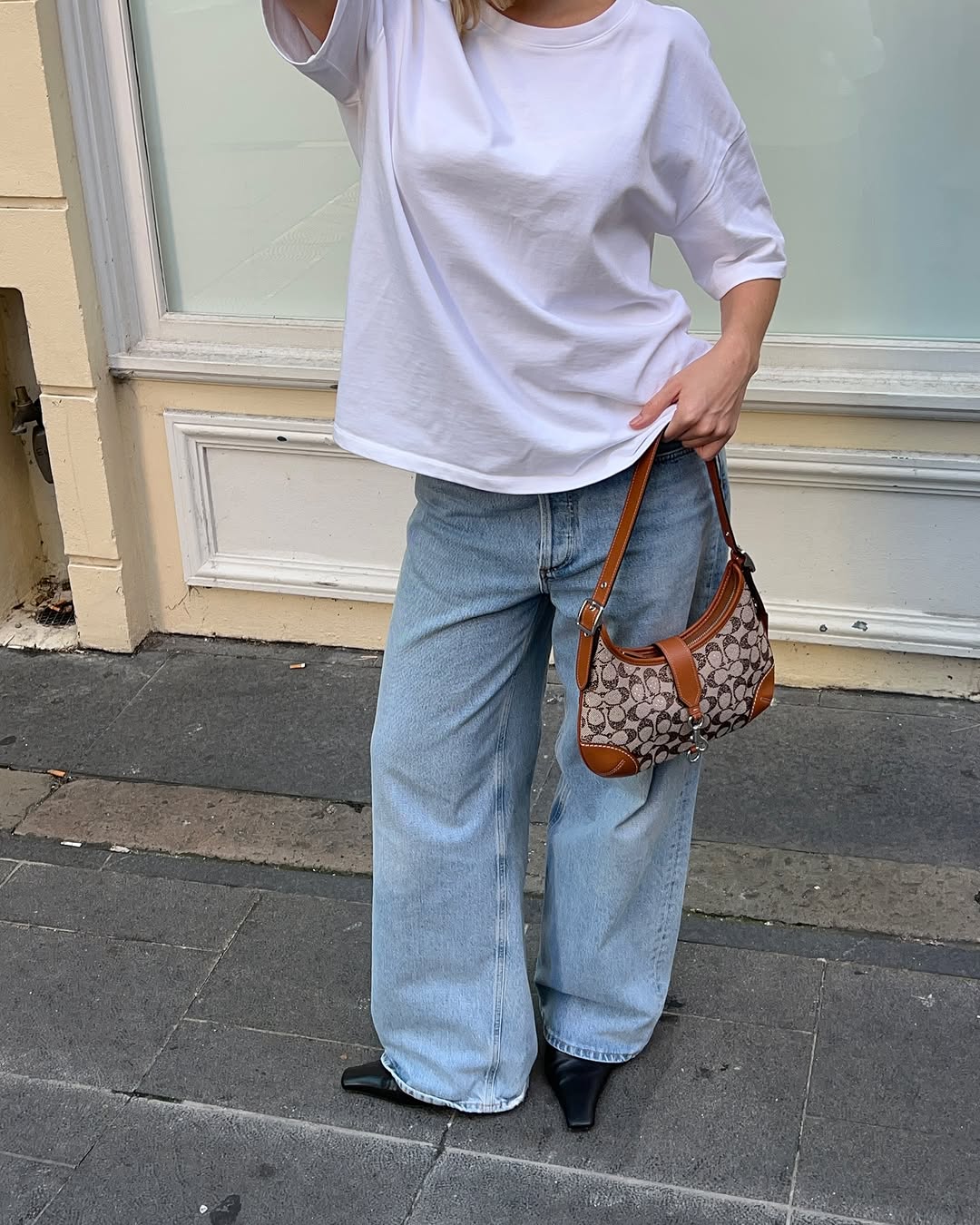 Woman wearing vintage jeans with white t shirt and cool bag.