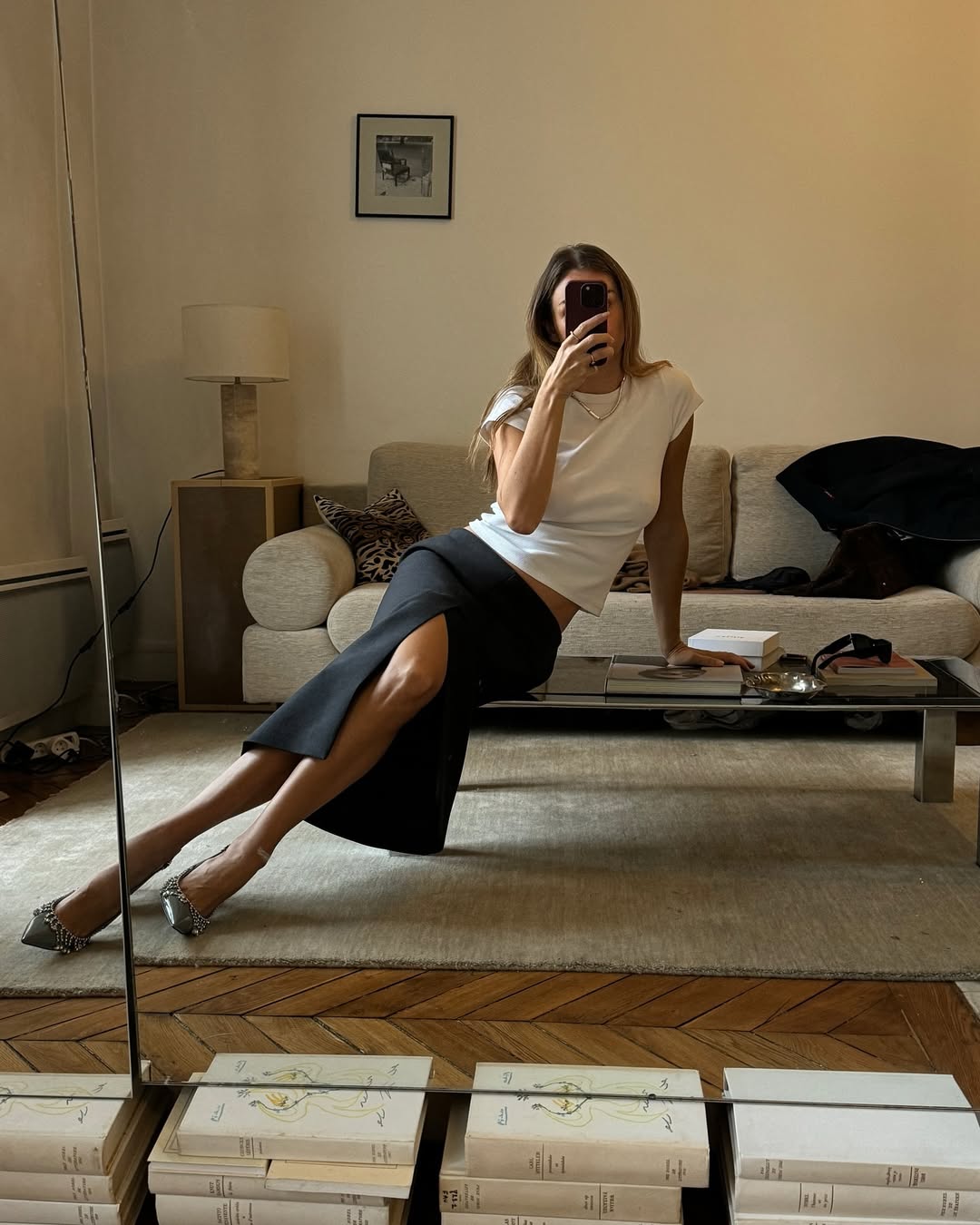 A woman wearing white t-shirt and knee-length skirt summer 2025.