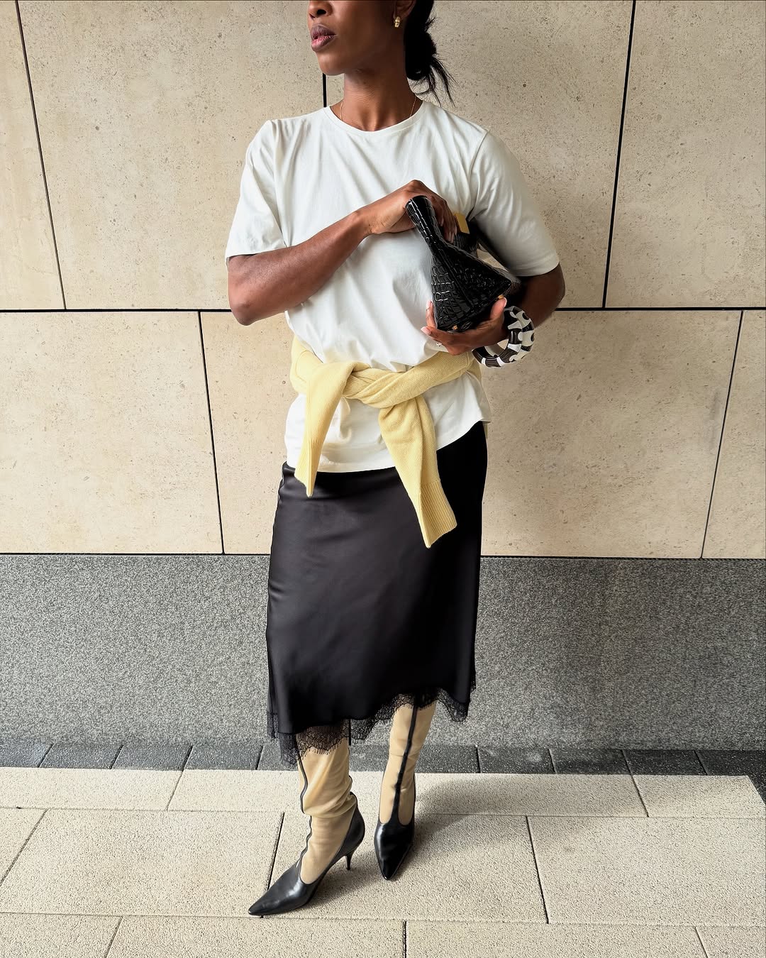 A woman wearing white t-shirt and knee-length skirt summer 2025.