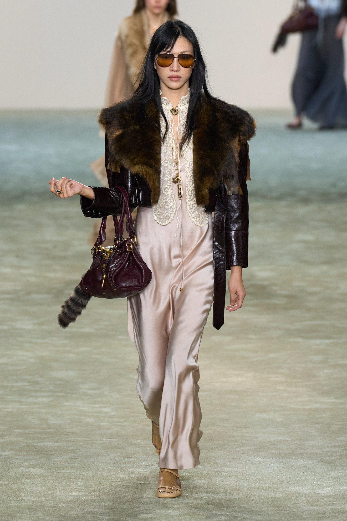A Chloé model at the F/W 25 show wearing a leather-and-fur jacket with a silk-and-lace slip dress. 
