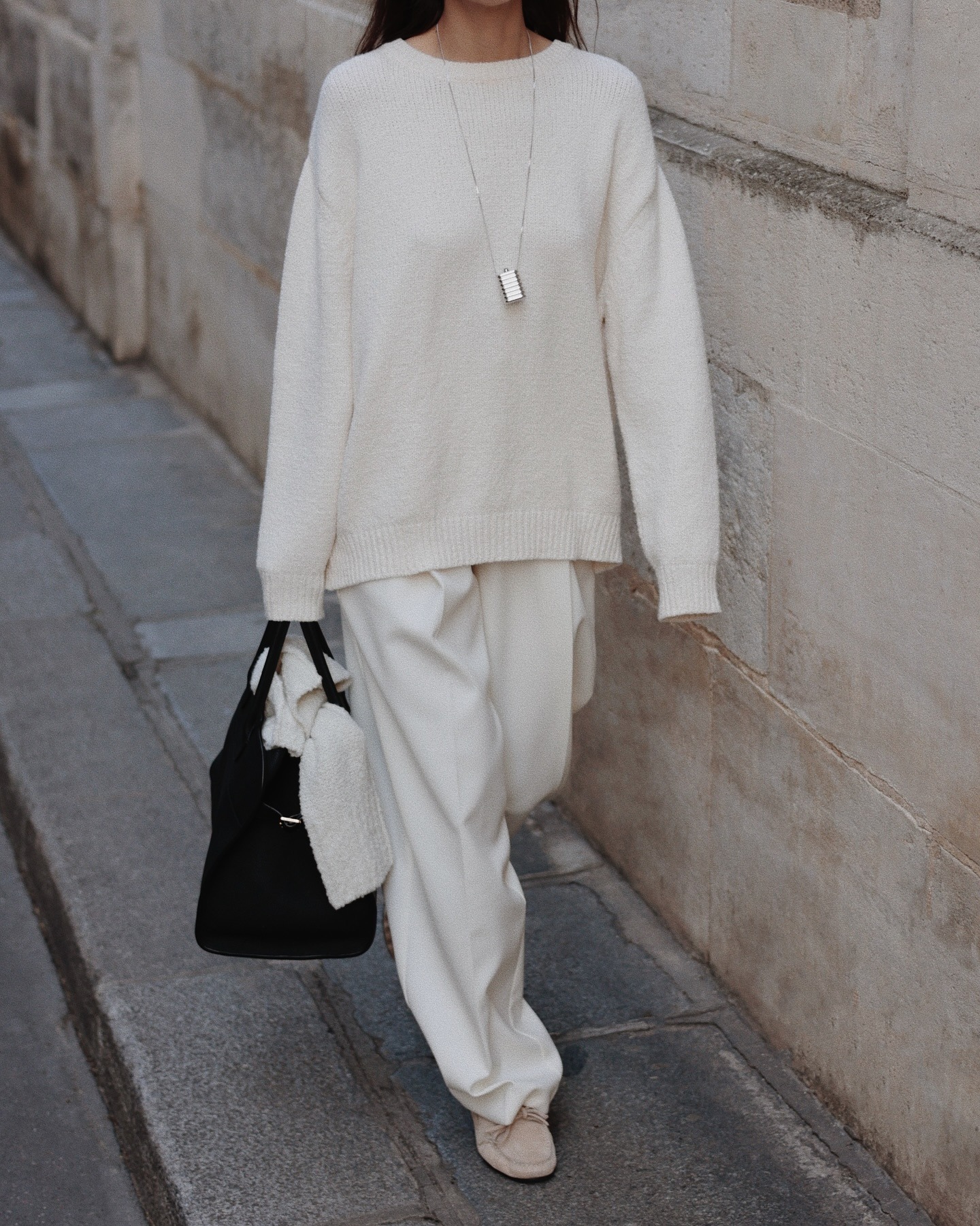 @modedamour wearing a loose cream sweatshirt with slouchy white trousers and loafers.