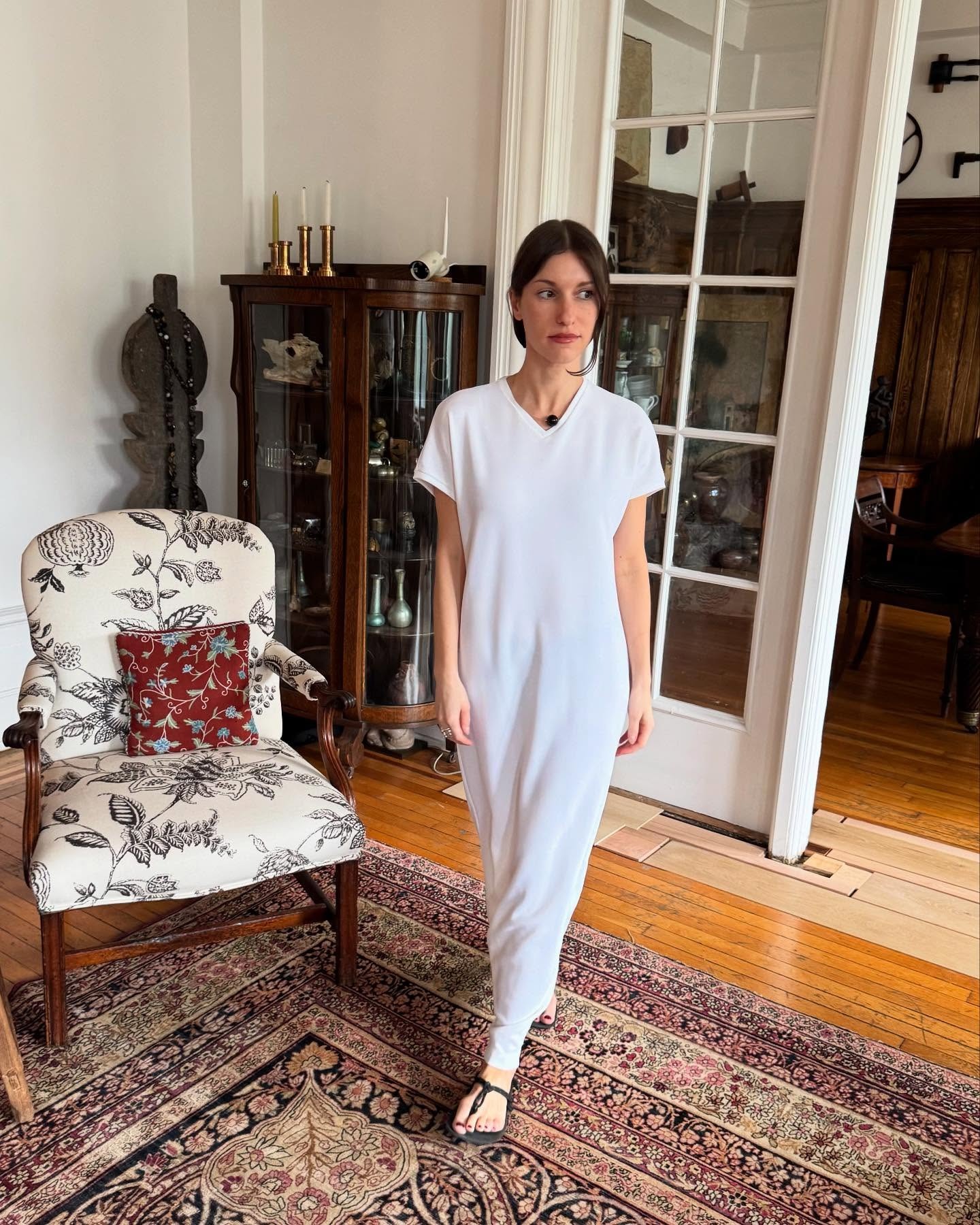 Laura Reilly wearing a white T-shirt dress and thong sandals.