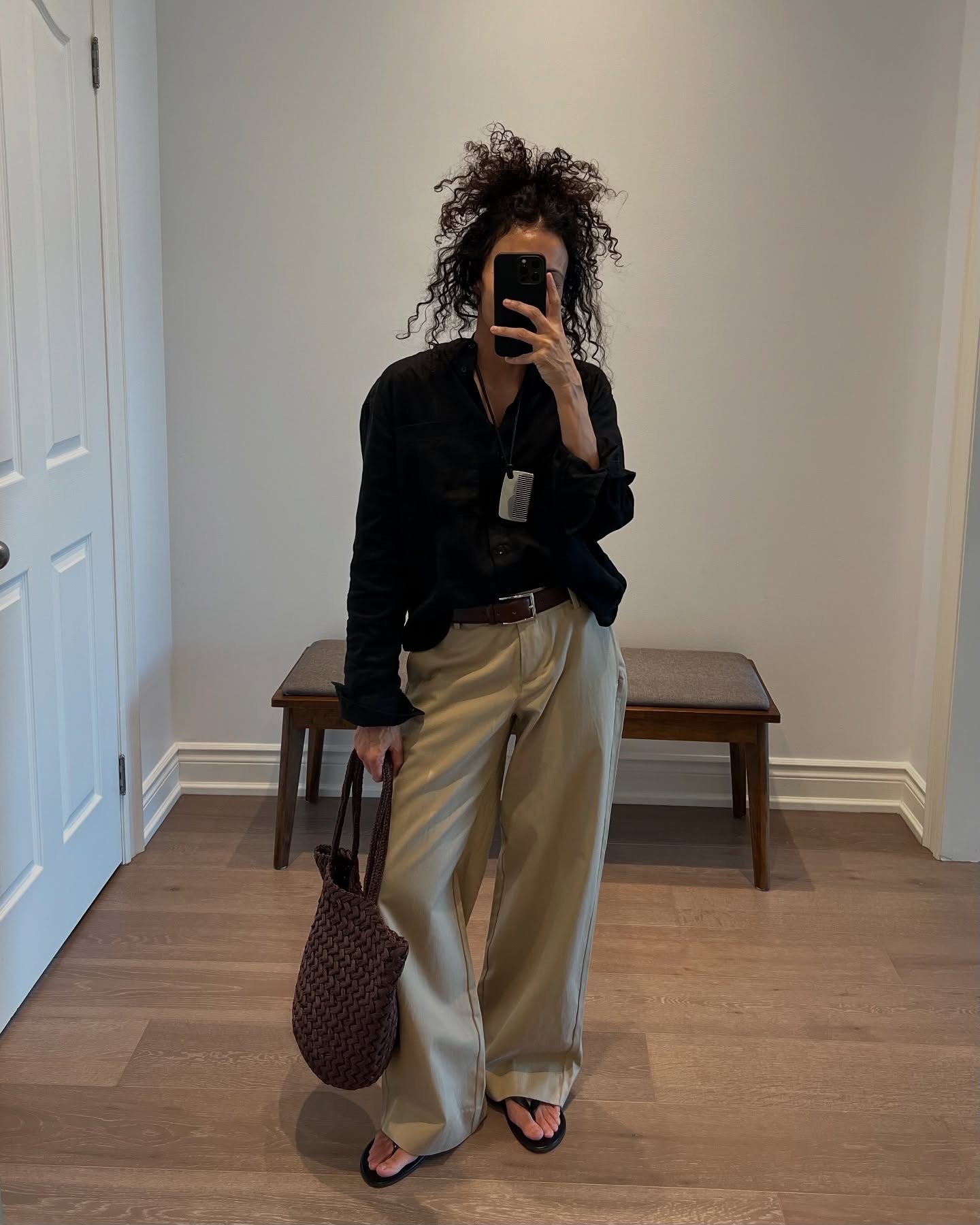 Neelam Ahooja wearing a black button-down shirt with khaki loose pants and flip flops.